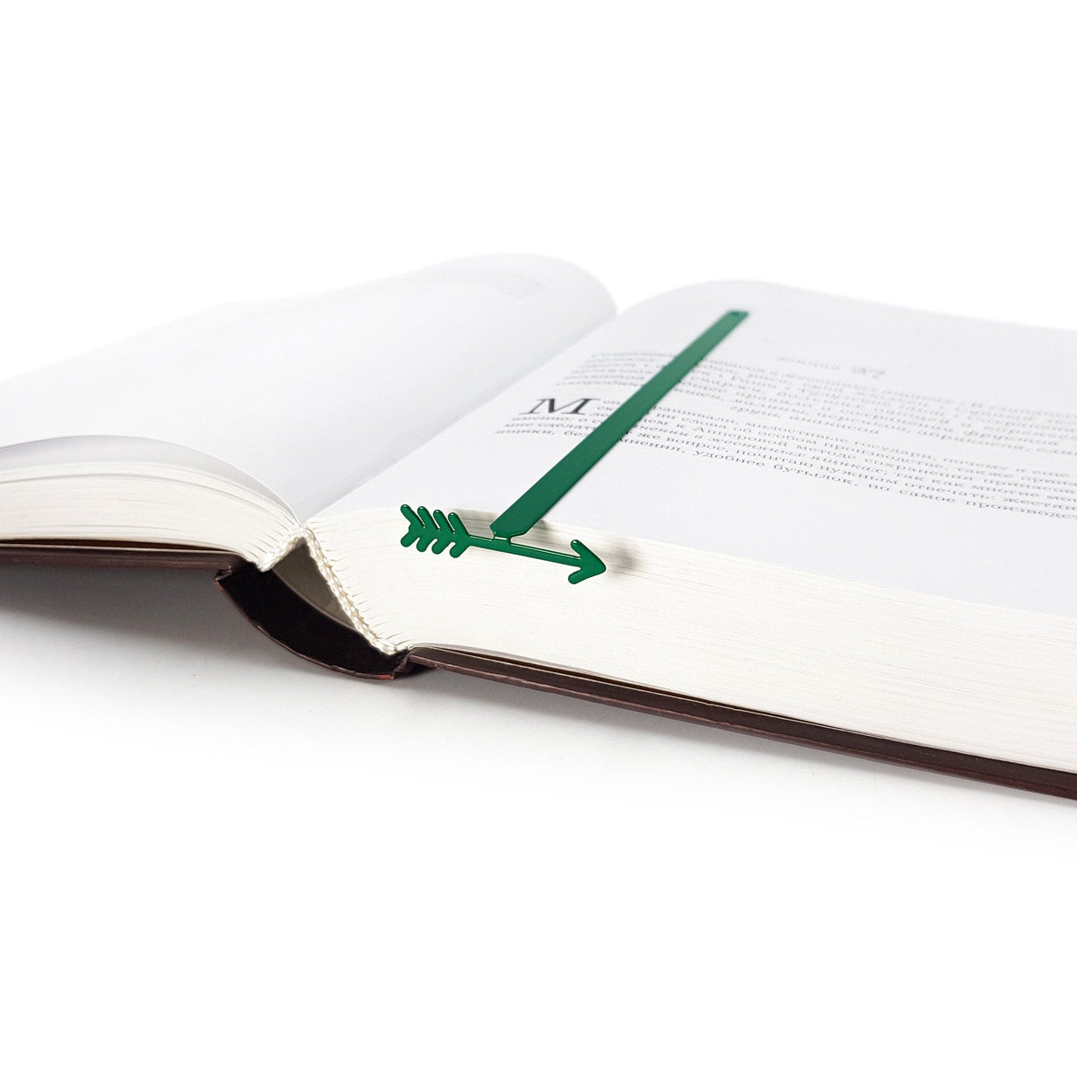Arrow metal bookmark in green set into the gutter of an open book