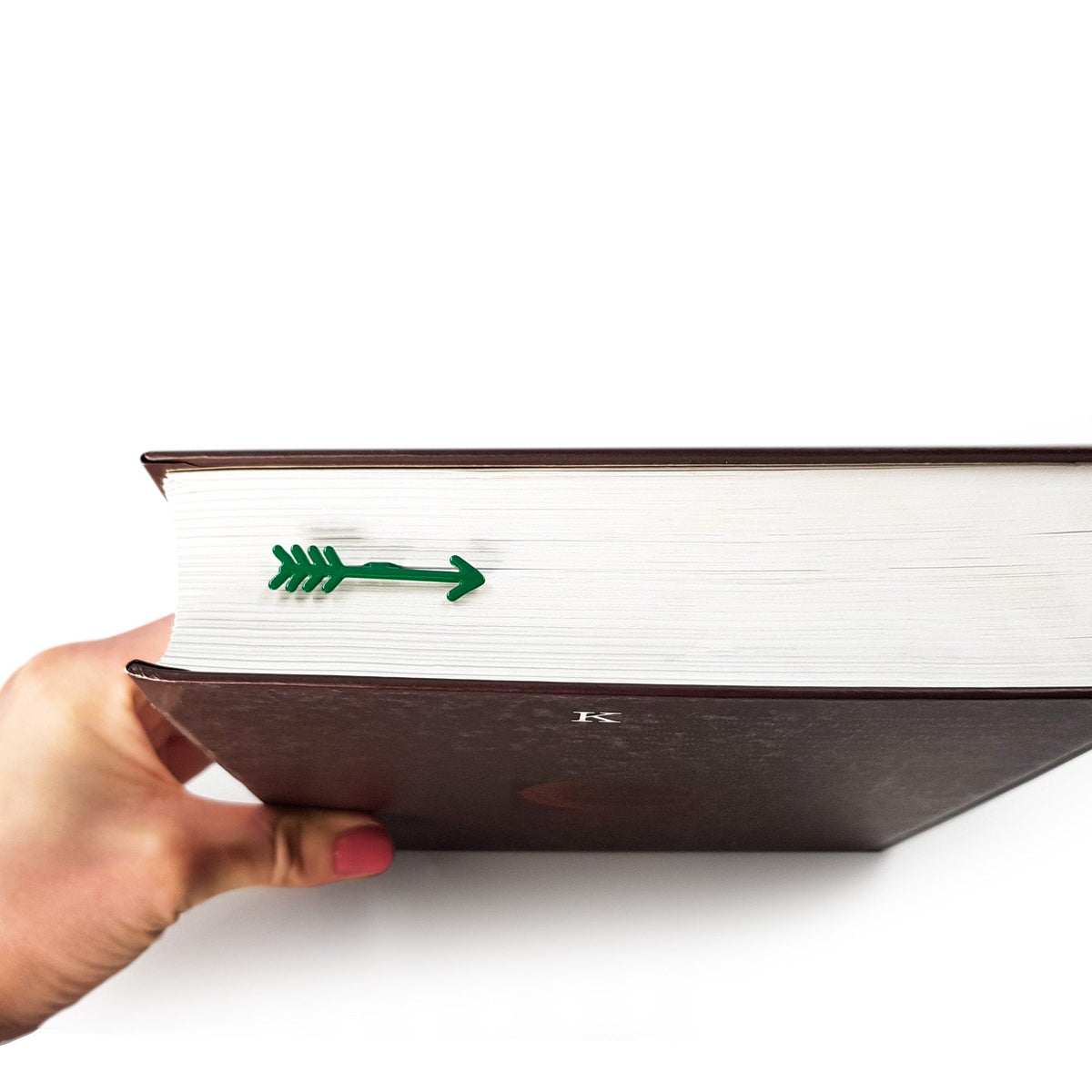 Arrow metal bookmark in gold clipped in a closed book, viewed from the side