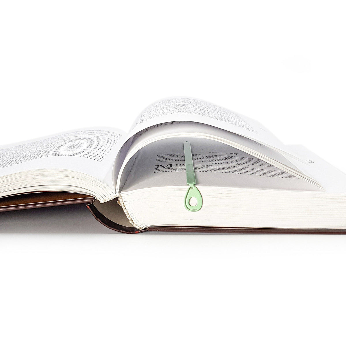 Avocado metal bookmark in green resting on the pages of an open book