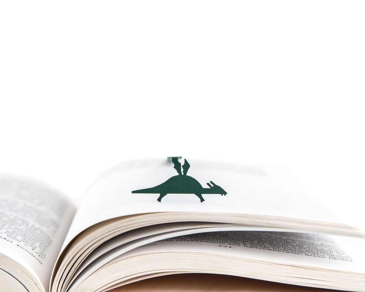 Baby Dinosaur metal bookmark in green resting on the pages of an open book