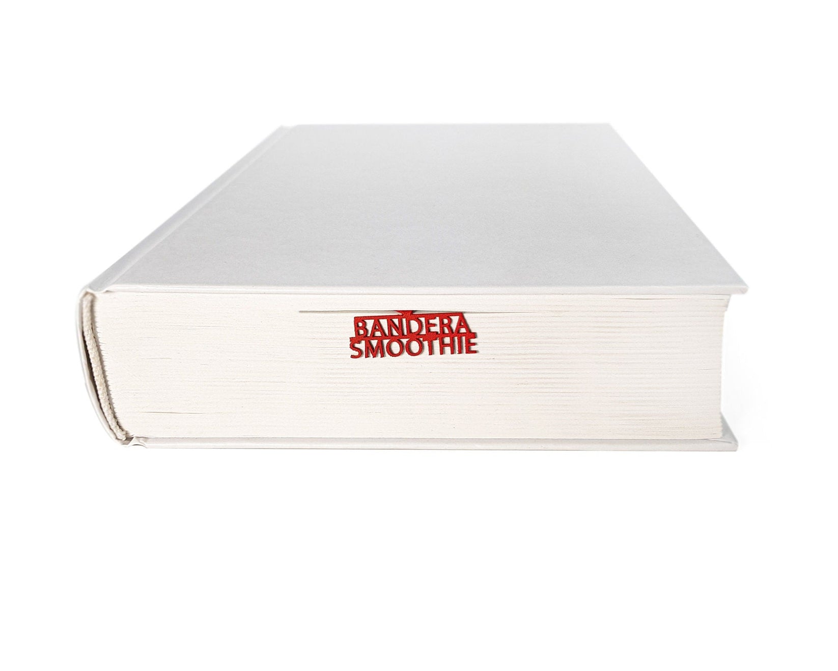 Bandera Smoothie metal bookmark in red in a closed book, only its top showing above the pages