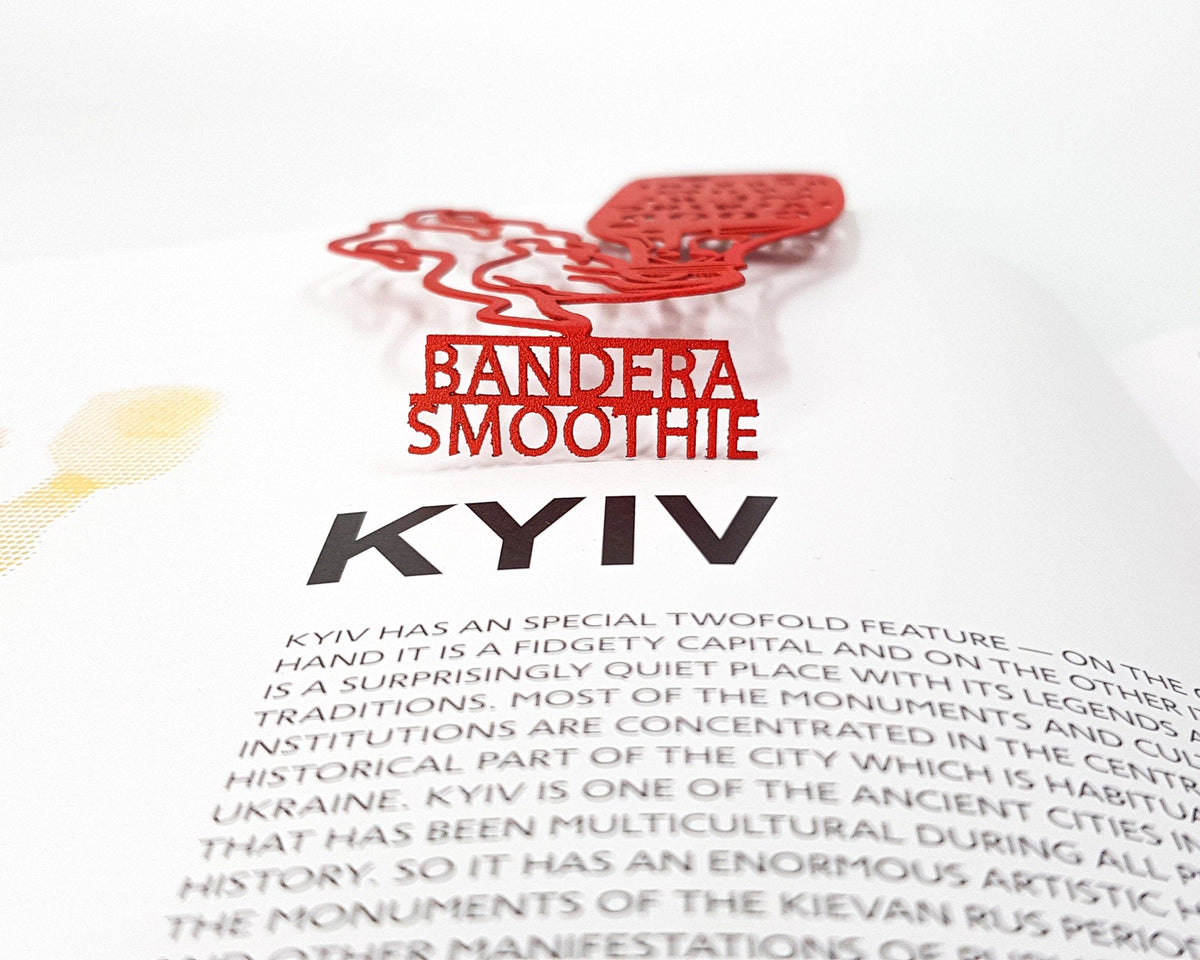 Bandera Smoothie metal bookmark in red marking a page in an open book