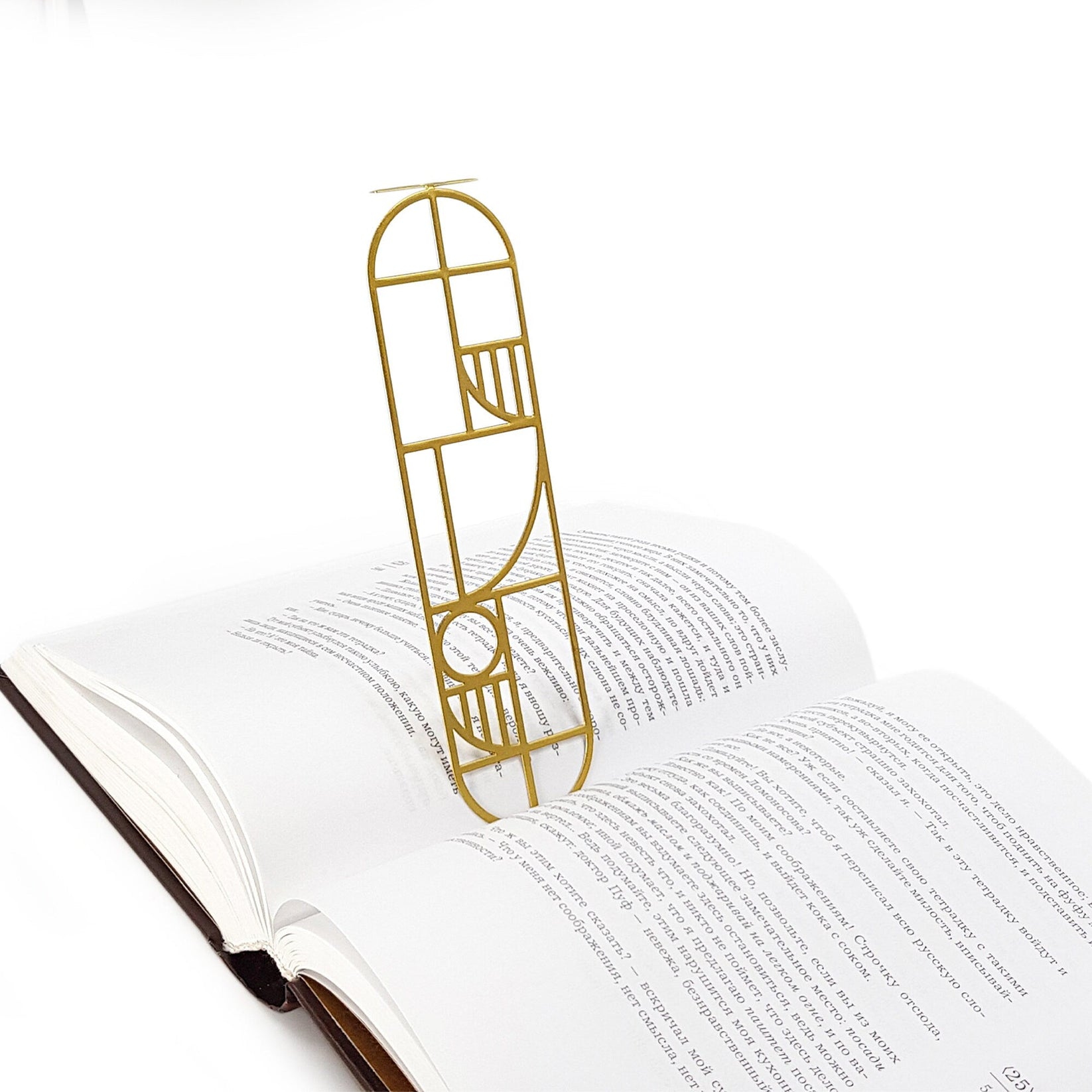 Bauhaus Geometry metal bookmark in gold lying across the pages of an open book