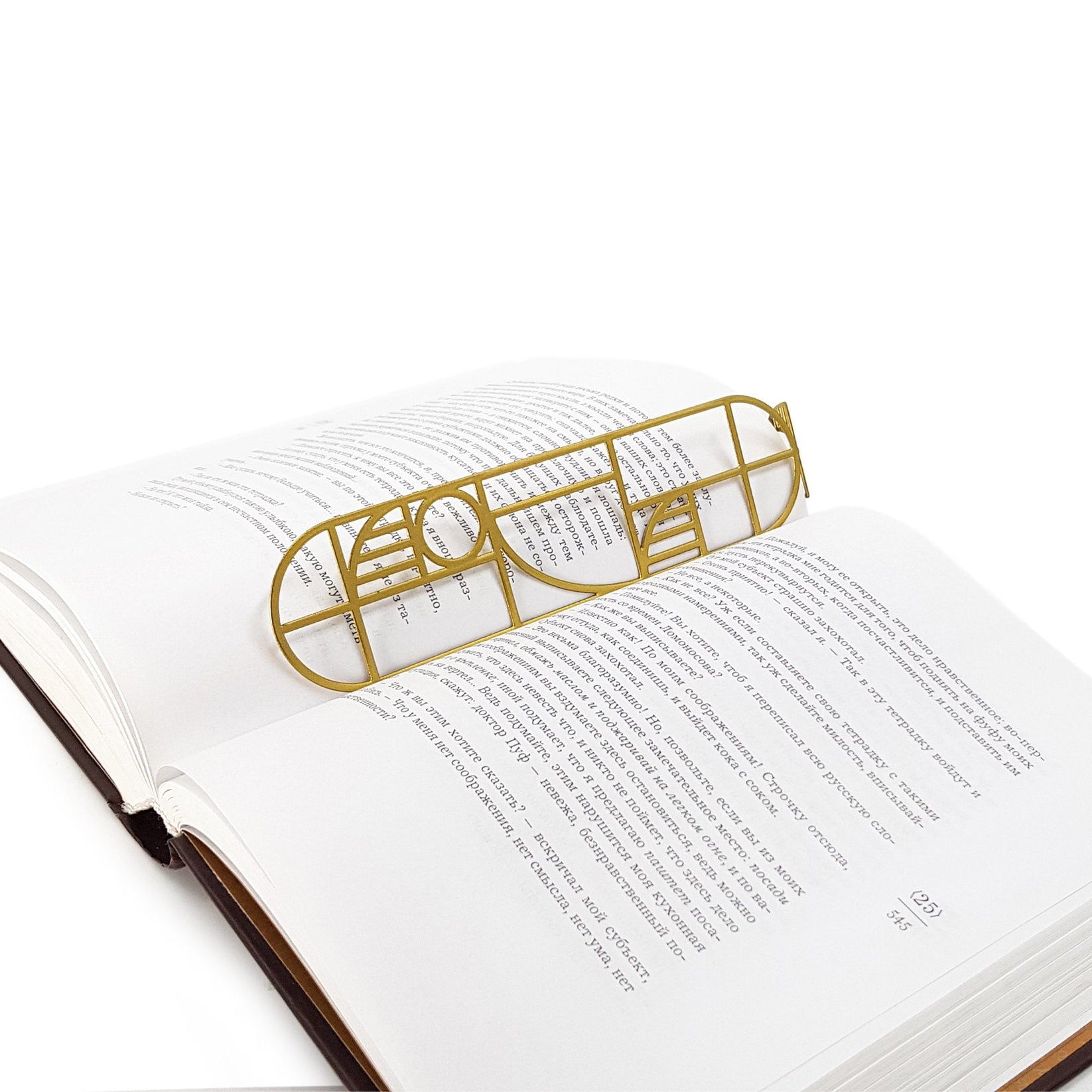 Bauhaus Geometry metal bookmark in gold set into the gutter of an open book