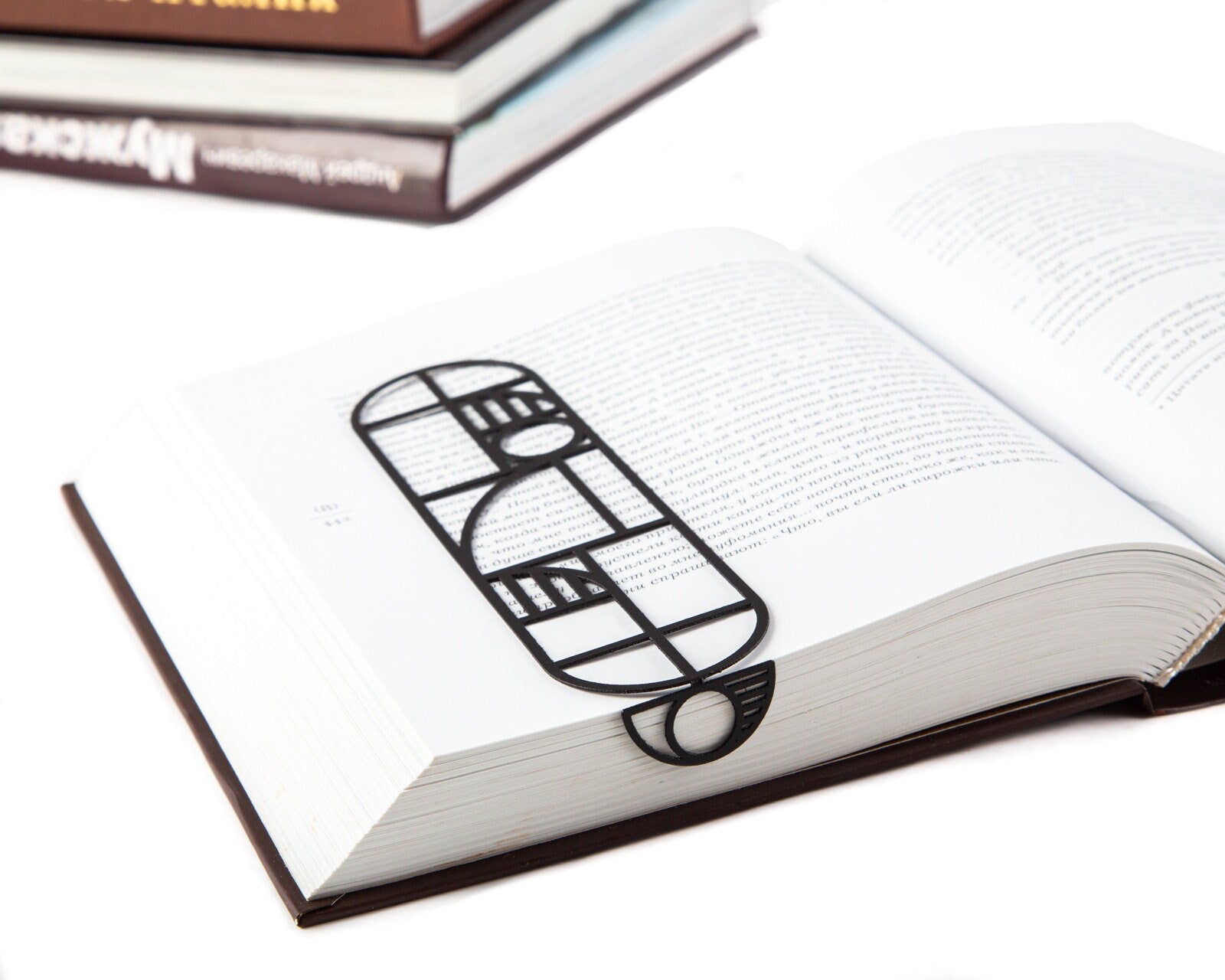 Bauhaus Geometry metal bookmark resting on the pages of an open book