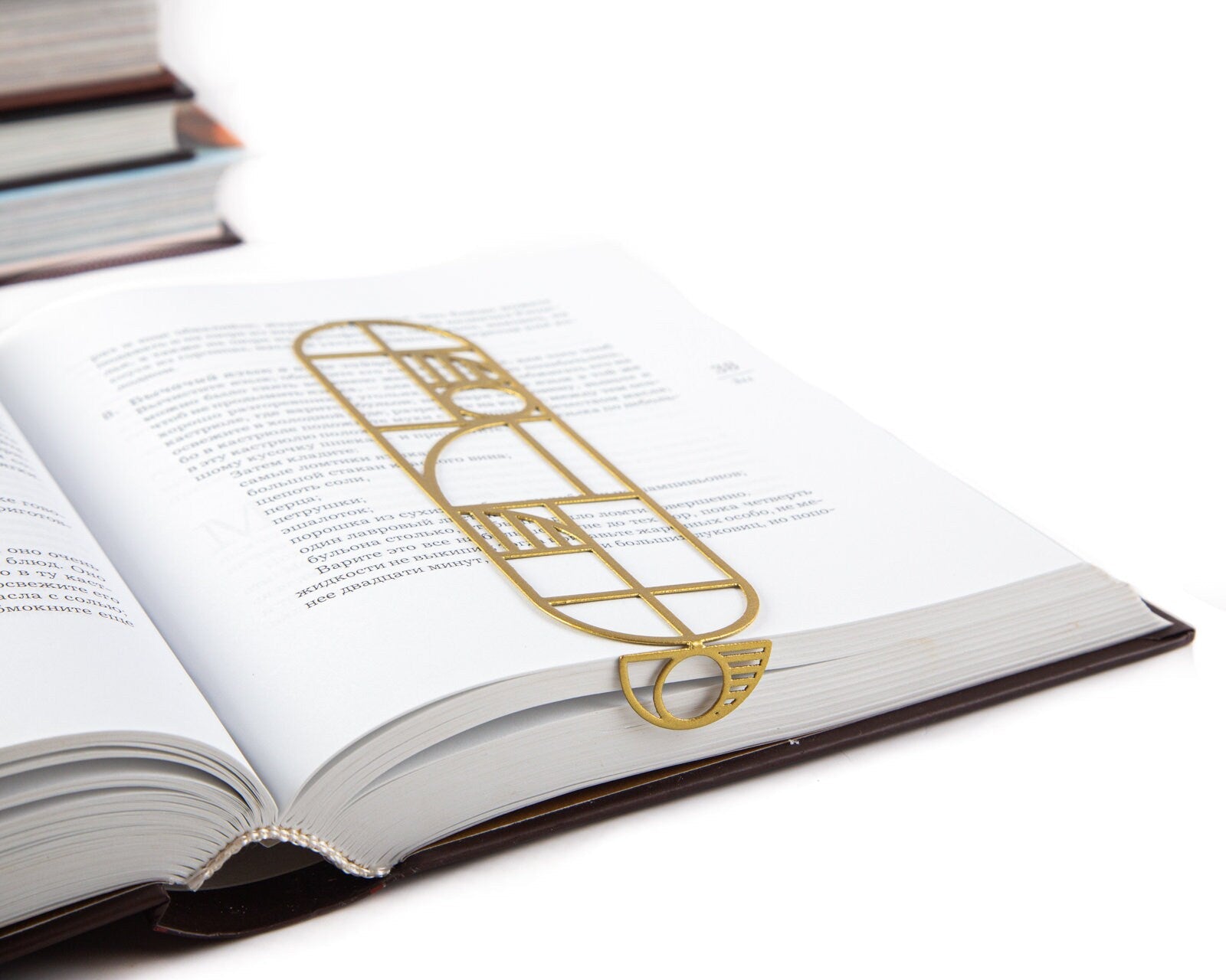 Bauhaus Geometry metal bookmark in gold marking a page in an open book
