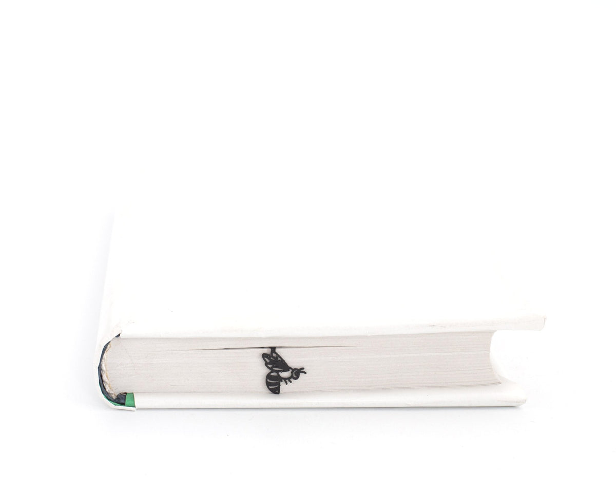 Beautiful Knapweed and the Bee metal bookmark in a closed book, only its top showing above the pages
