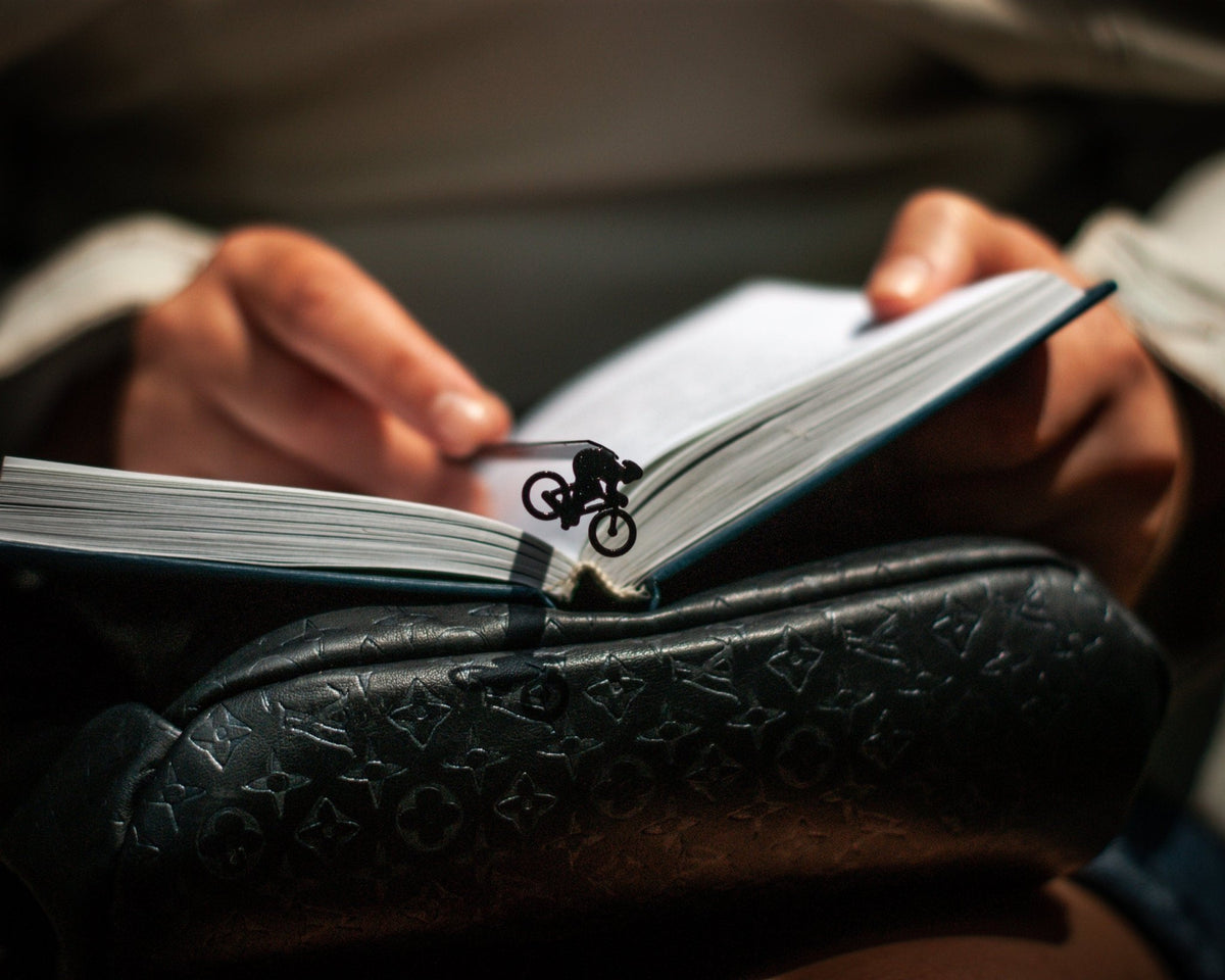 Bike Racing metal bookmark held in a hand above an open book