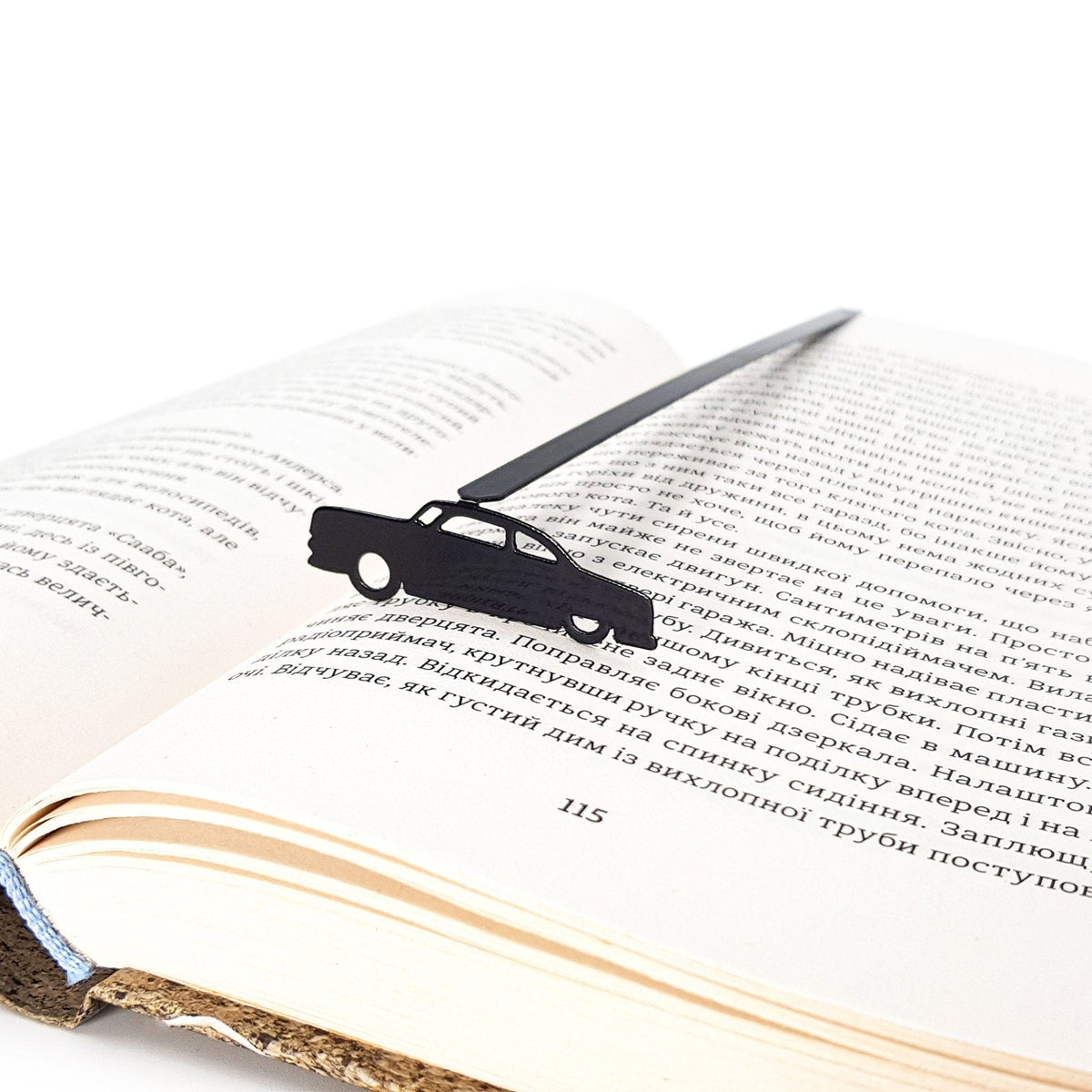 Black Car Phantom metal bookmark resting on the pages of an open book