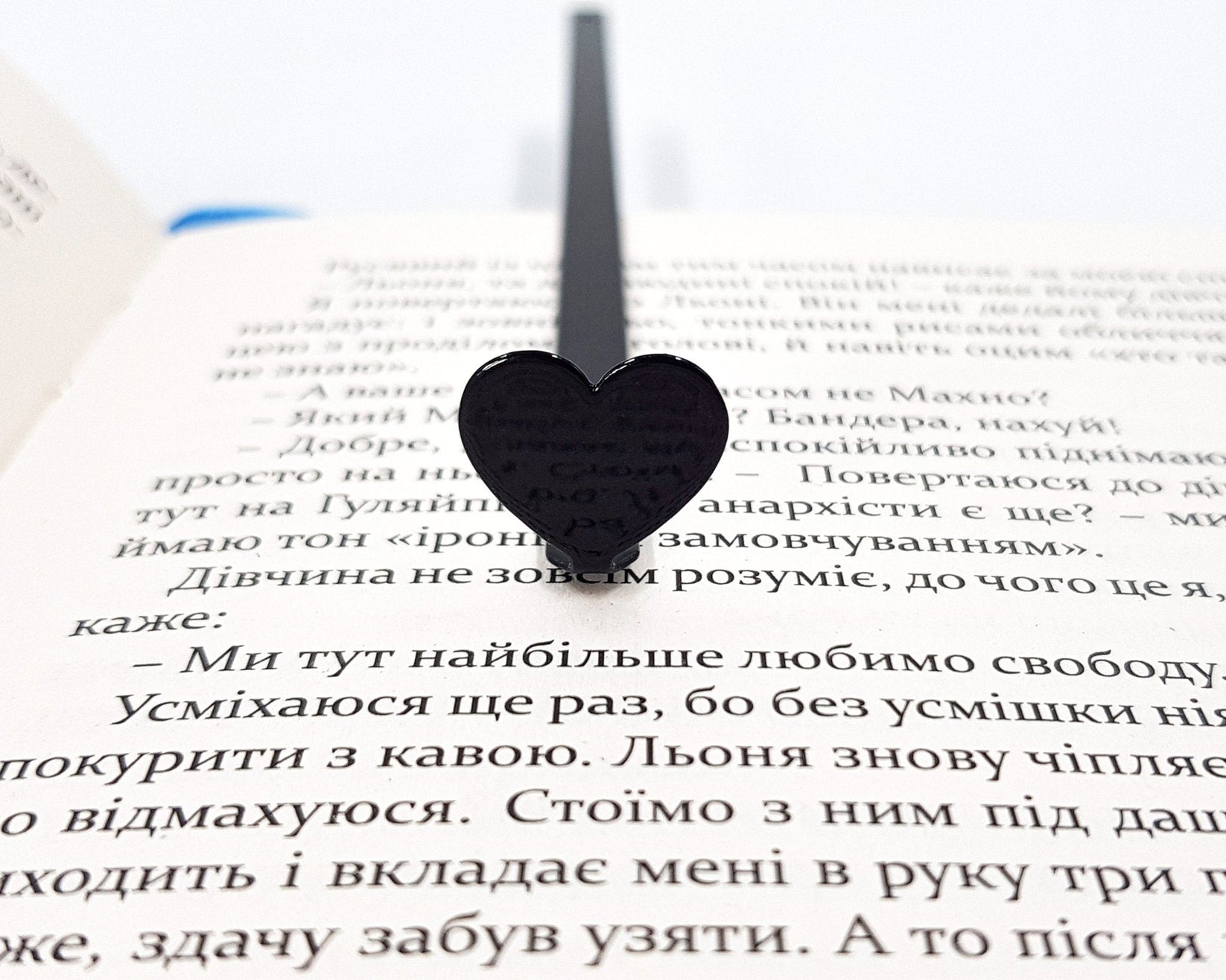 Black Heart metal bookmark resting on the pages of an open book