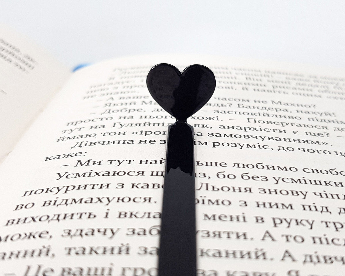Black Heart metal bookmark marking a page in an open book