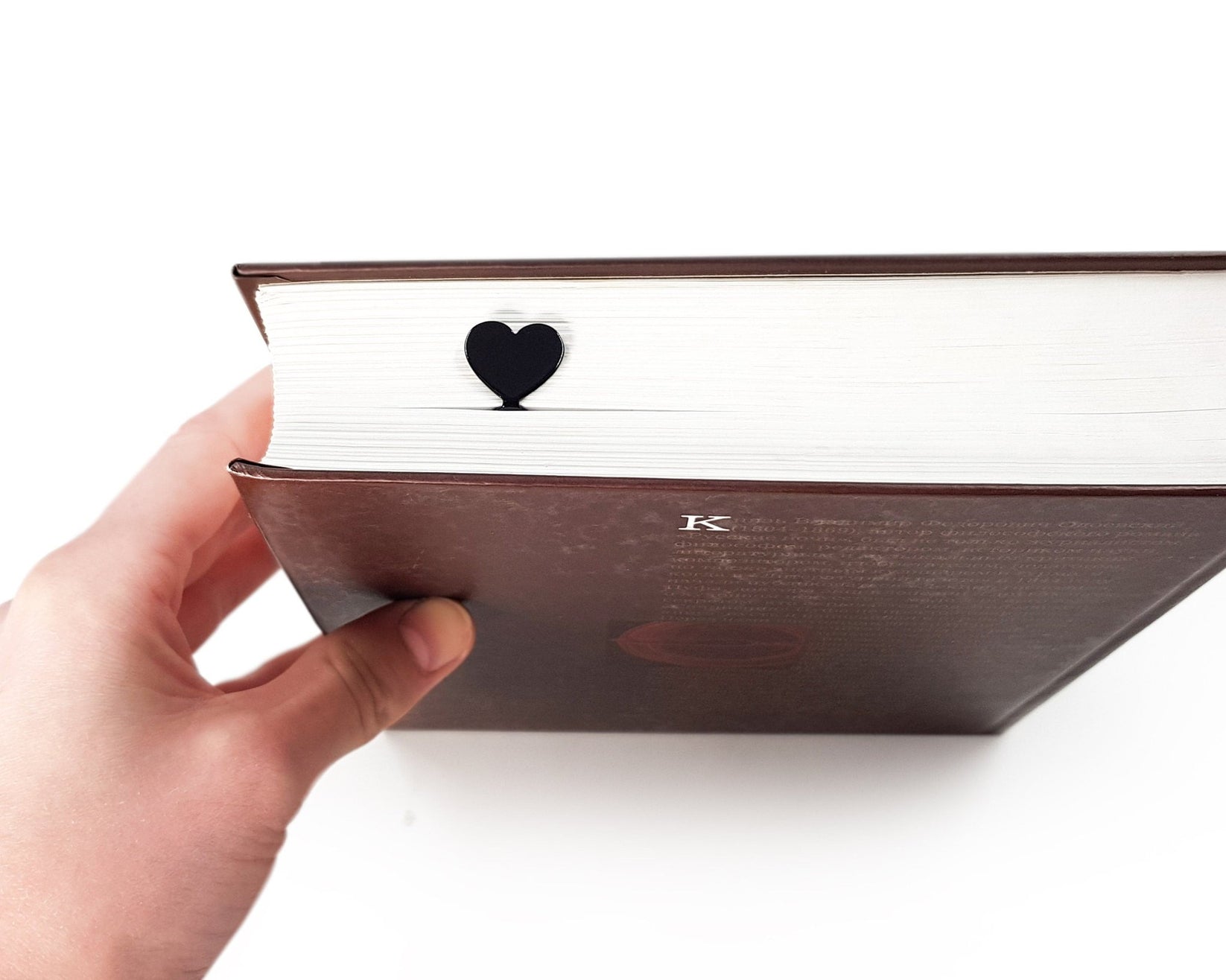Black Heart metal bookmark in a closed book, only its top showing above the pages