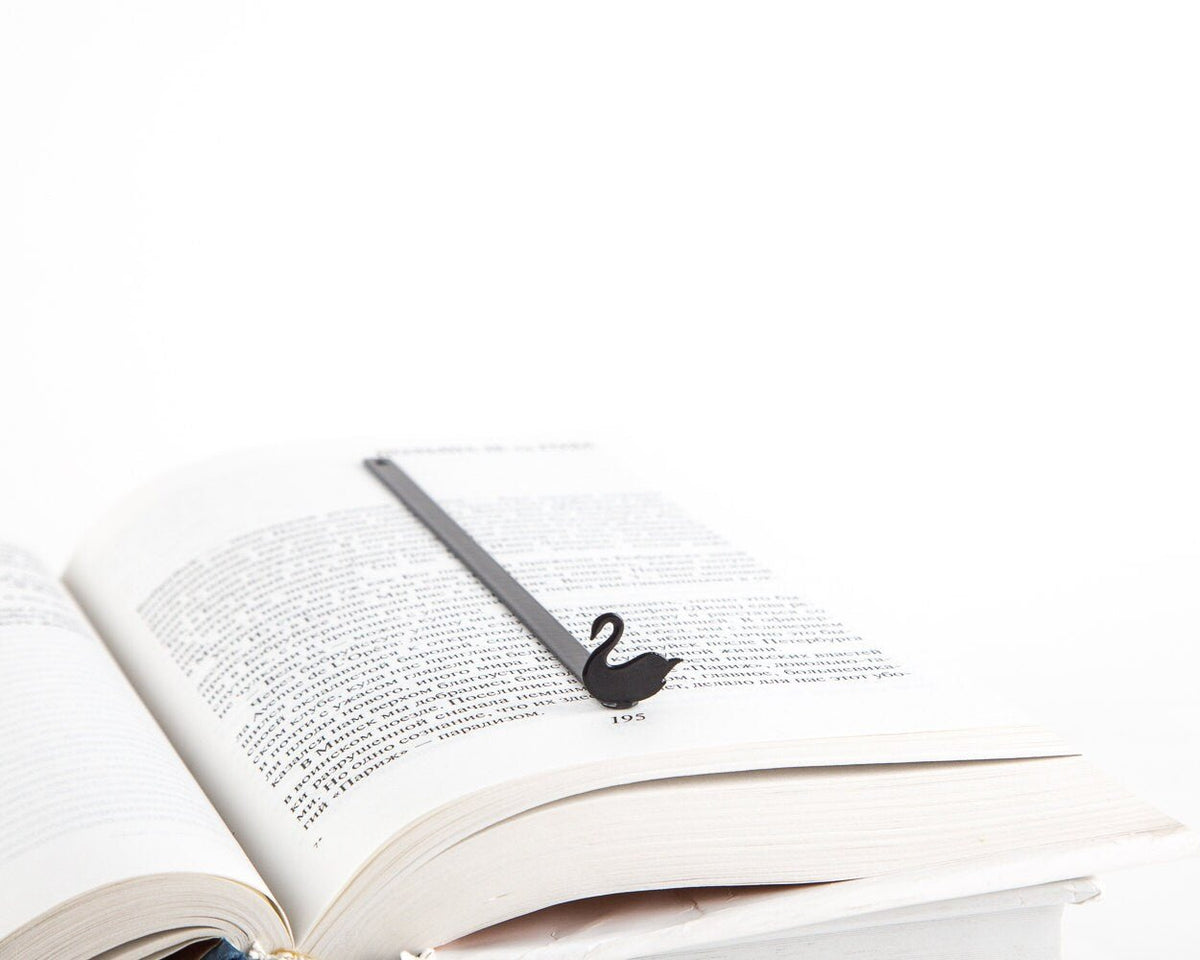 Black Swan metal bookmark resting on the pages of an open book