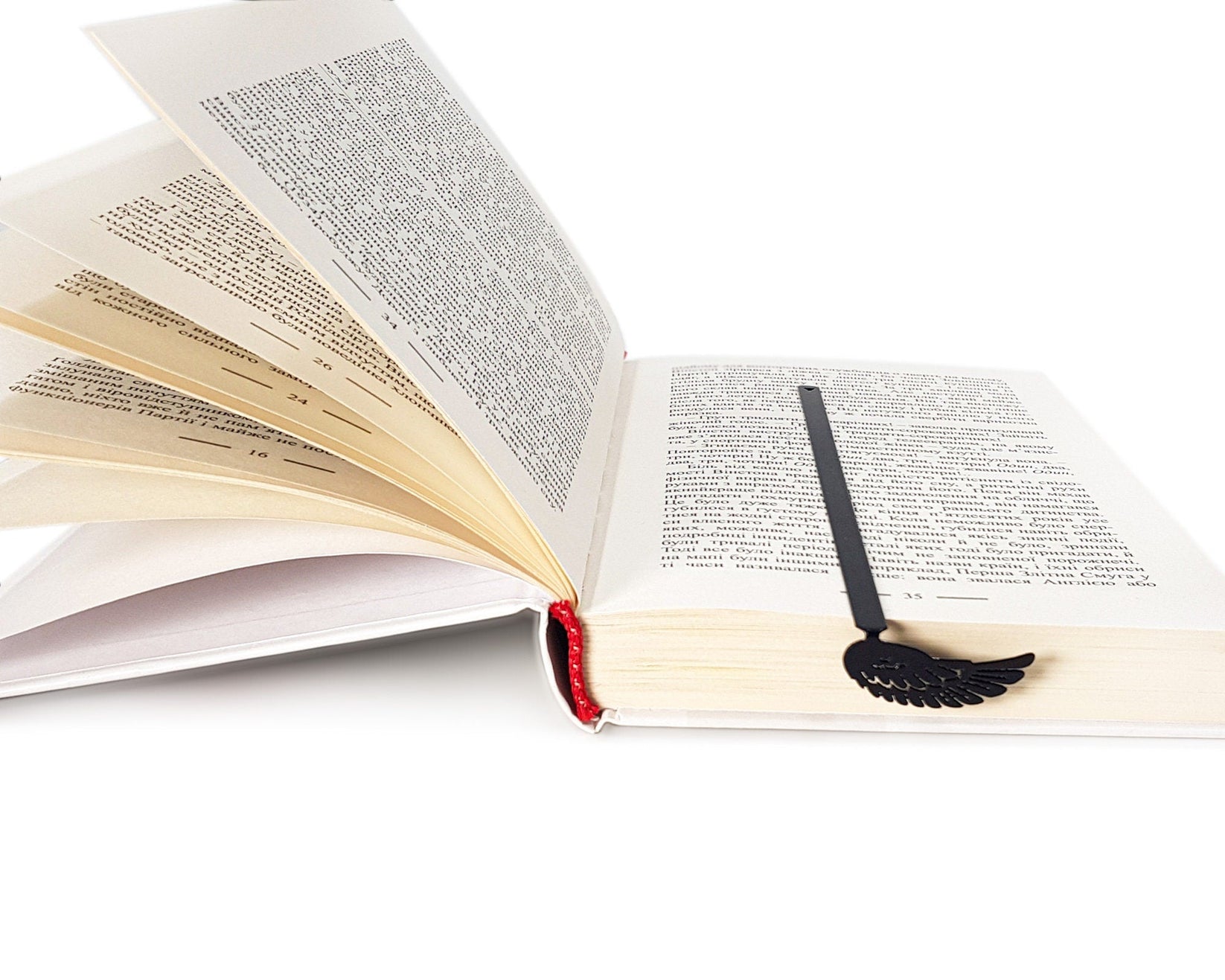 Black Wing metal bookmark resting on the pages of an open book