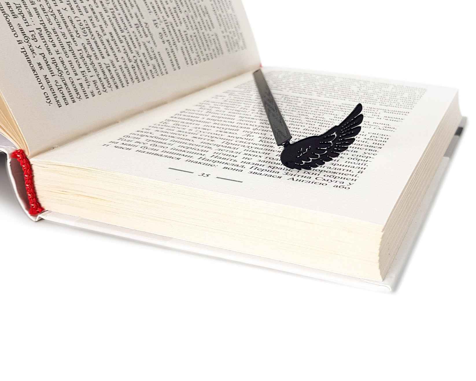 Black Wing metal bookmark seen from the edge of a closed book
