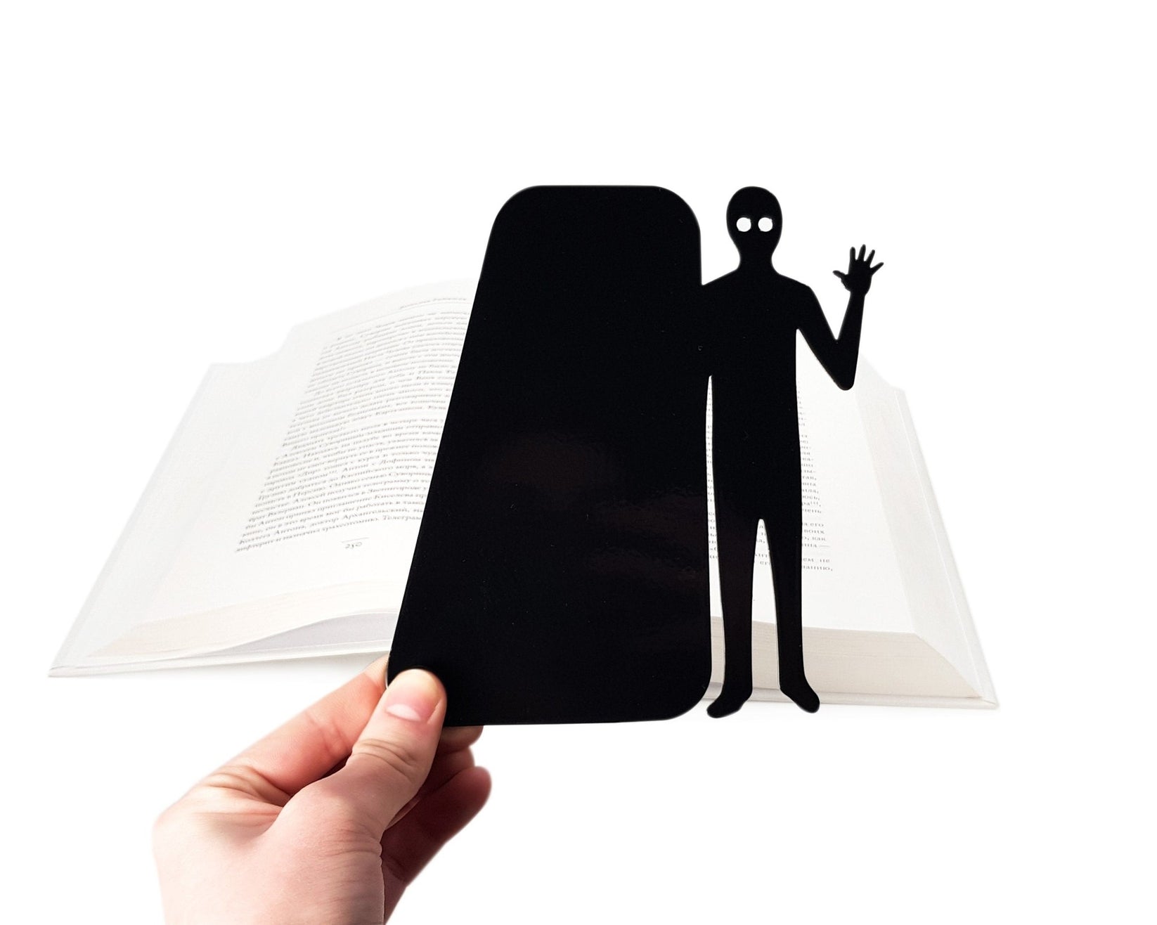 Book Ghost Coming Out metal bookmark held in a hand above an open book