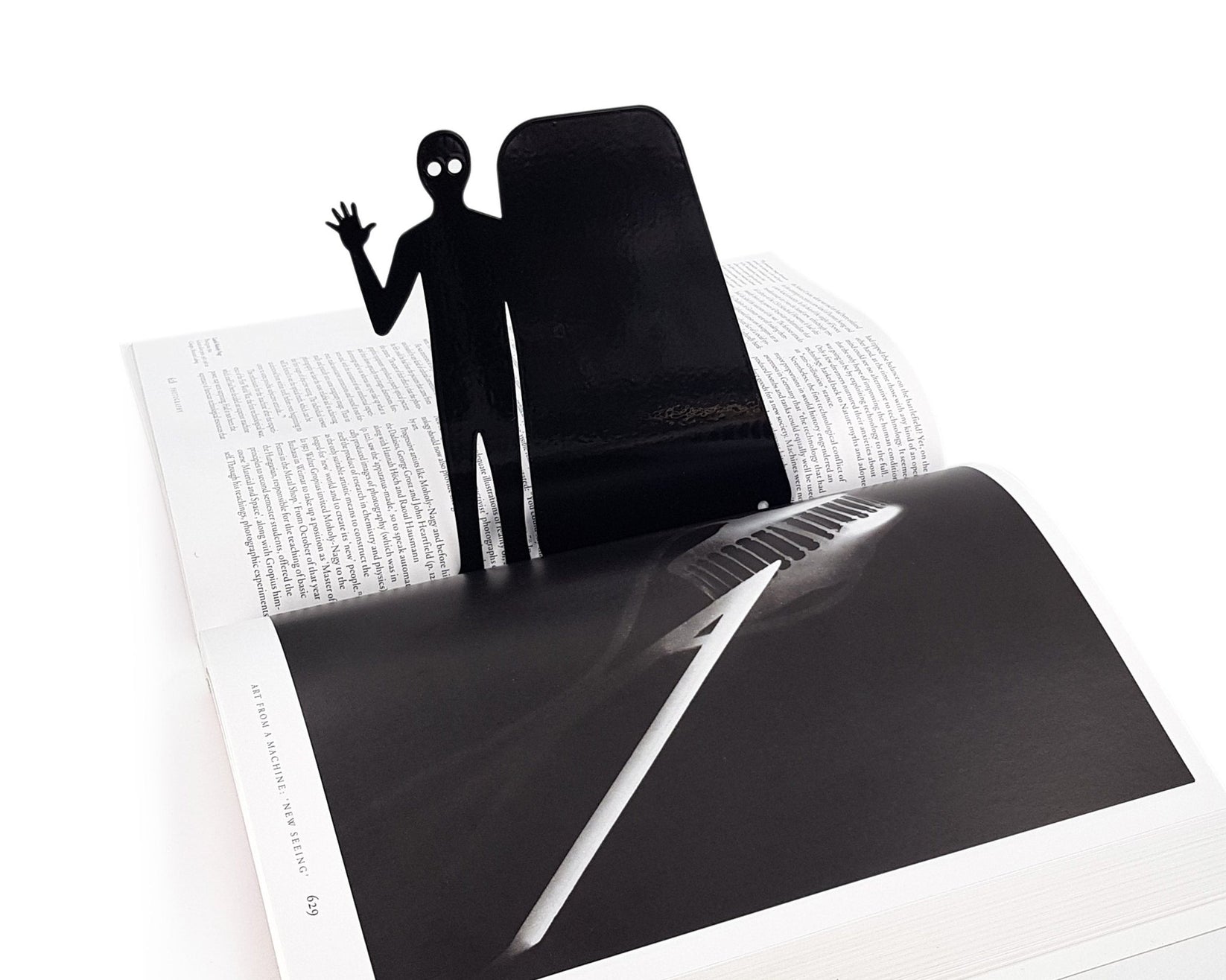 Book Ghost Coming Out metal bookmark resting on the pages of an open book