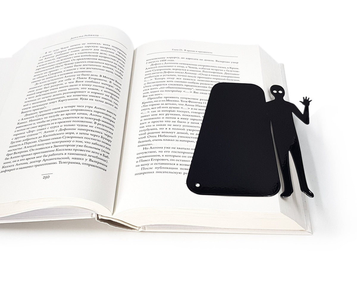 Book Ghost Coming Out metal bookmark marking a page in an open book