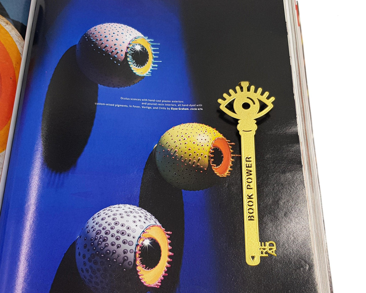 Book Power Is the Key metal bookmark in gold marking a page in an illustrated book