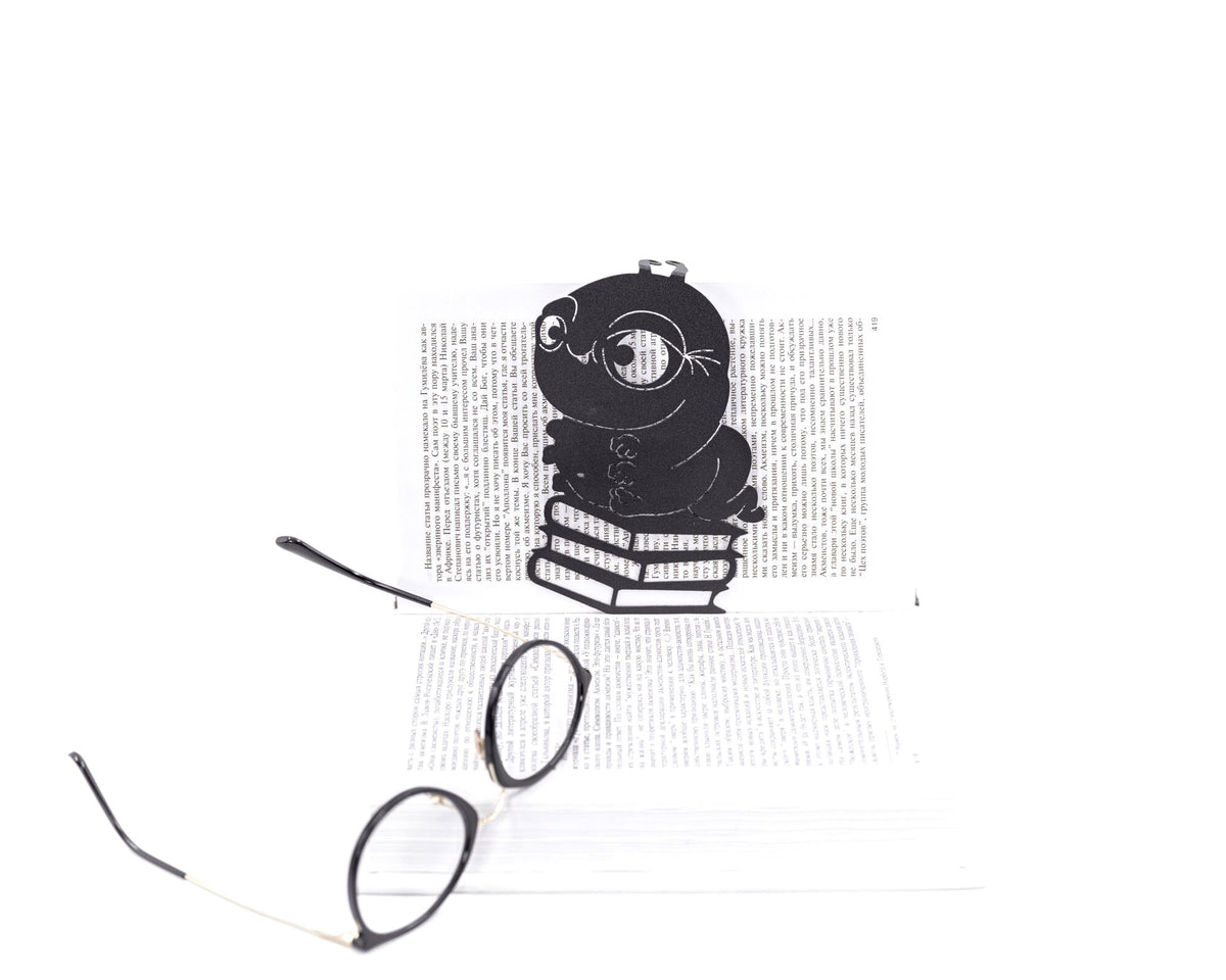 Bookworm metal bookmark in green resting on the pages of an open book