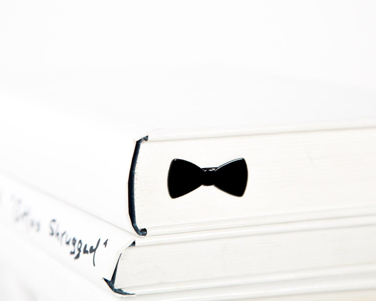 Bow Tie metal bookmark marking a page in an open book