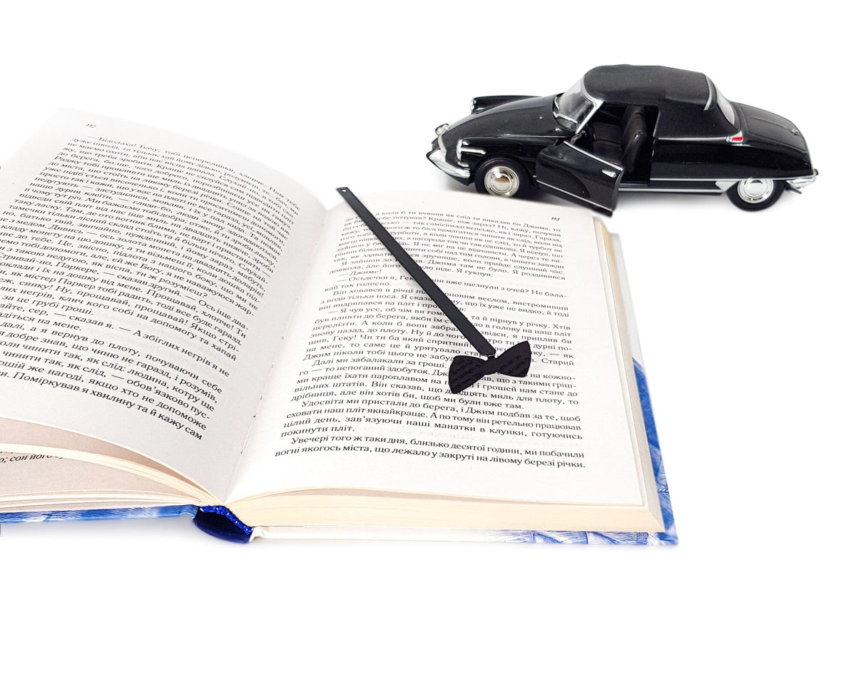 Bow Tie metal bookmark — open book beside black toy car