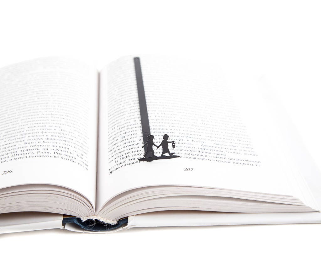 Boy and Girl metal bookmark marking a page in an open book
