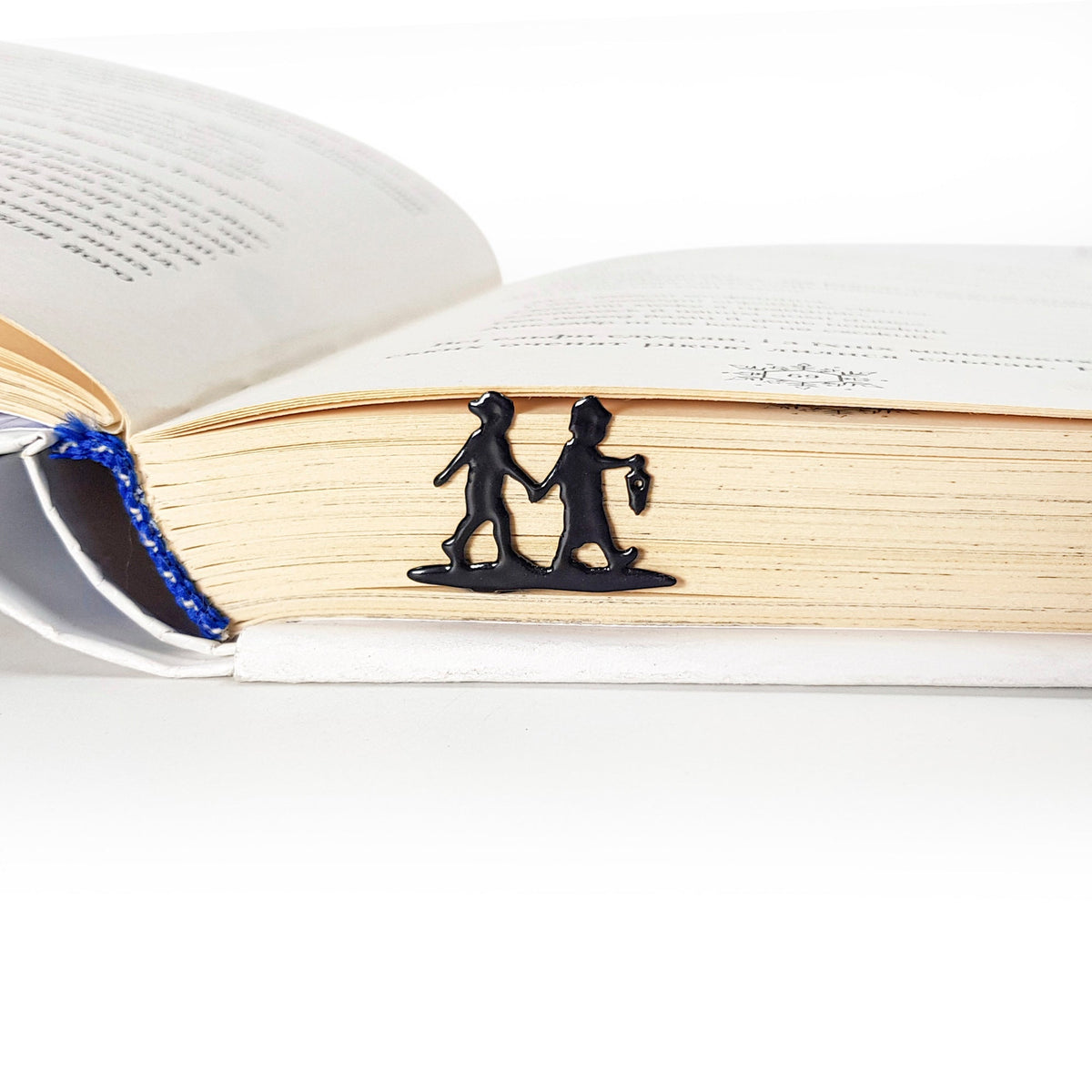 Boy and Girl metal bookmark resting on the pages of an open book