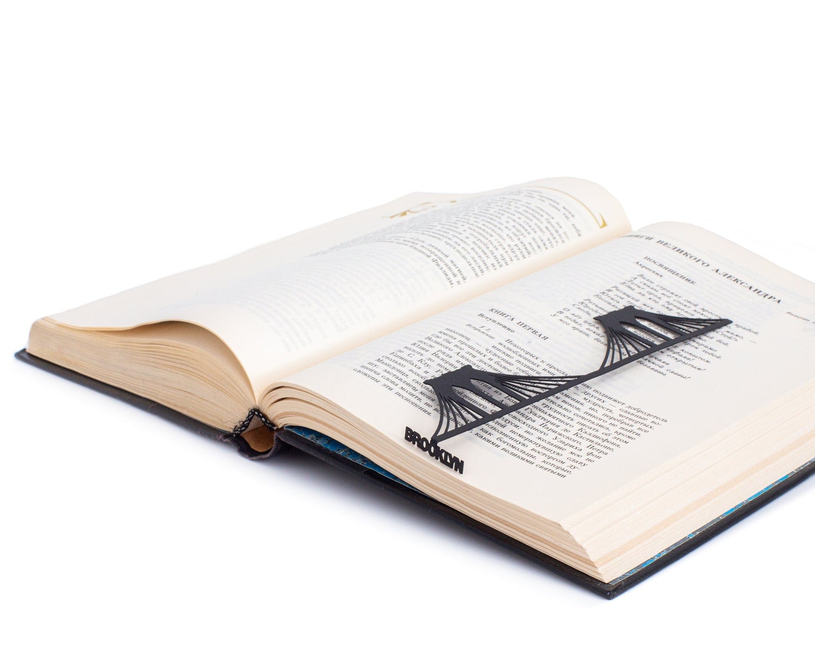 Brooklyn Bridge metal bookmark marking a page in an open book