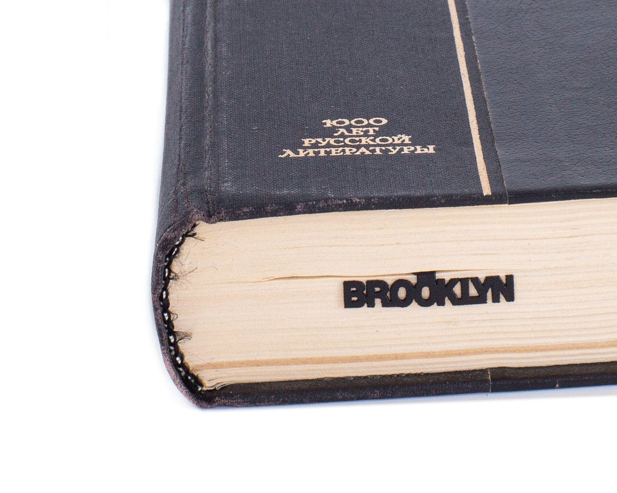 Brooklyn Bridge metal bookmark in a closed book, only its top showing above the pages