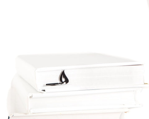 Burning Lucifer Match metal bookmark shown with a stack of books