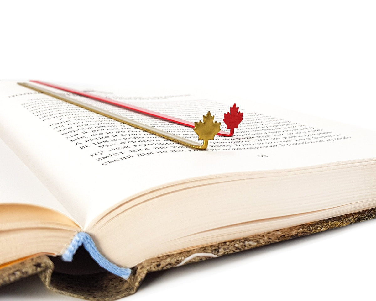Canadian Maple Leaf metal bookmark in red set into the gutter of an open book