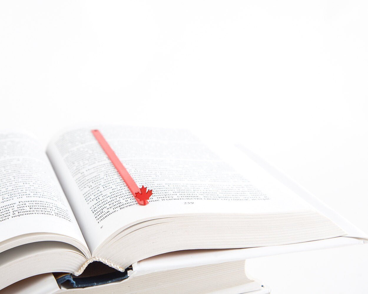 Canadian Maple Leaf metal bookmark in red marking a page in an open book