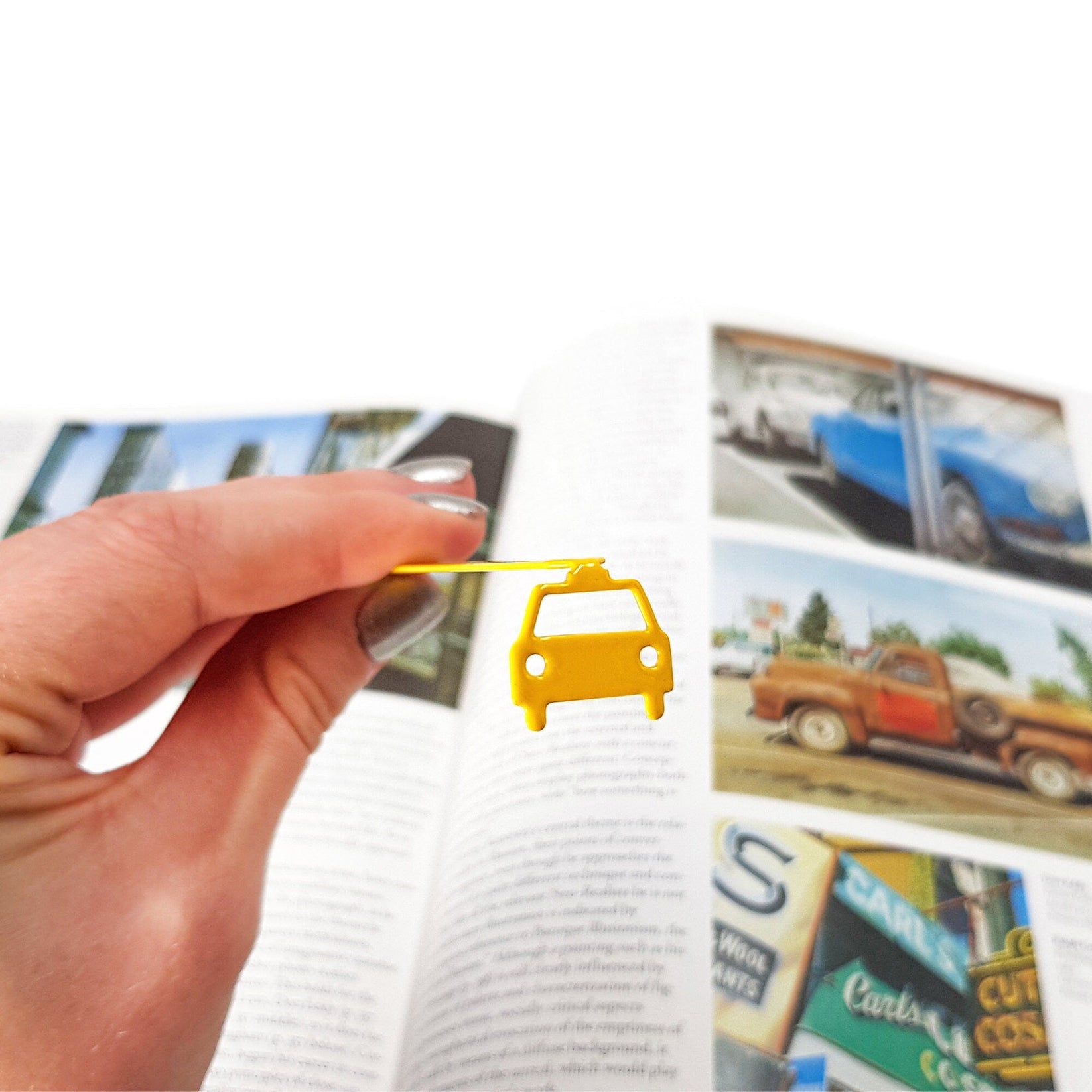Car metal bookmark in gold held up beside an open book