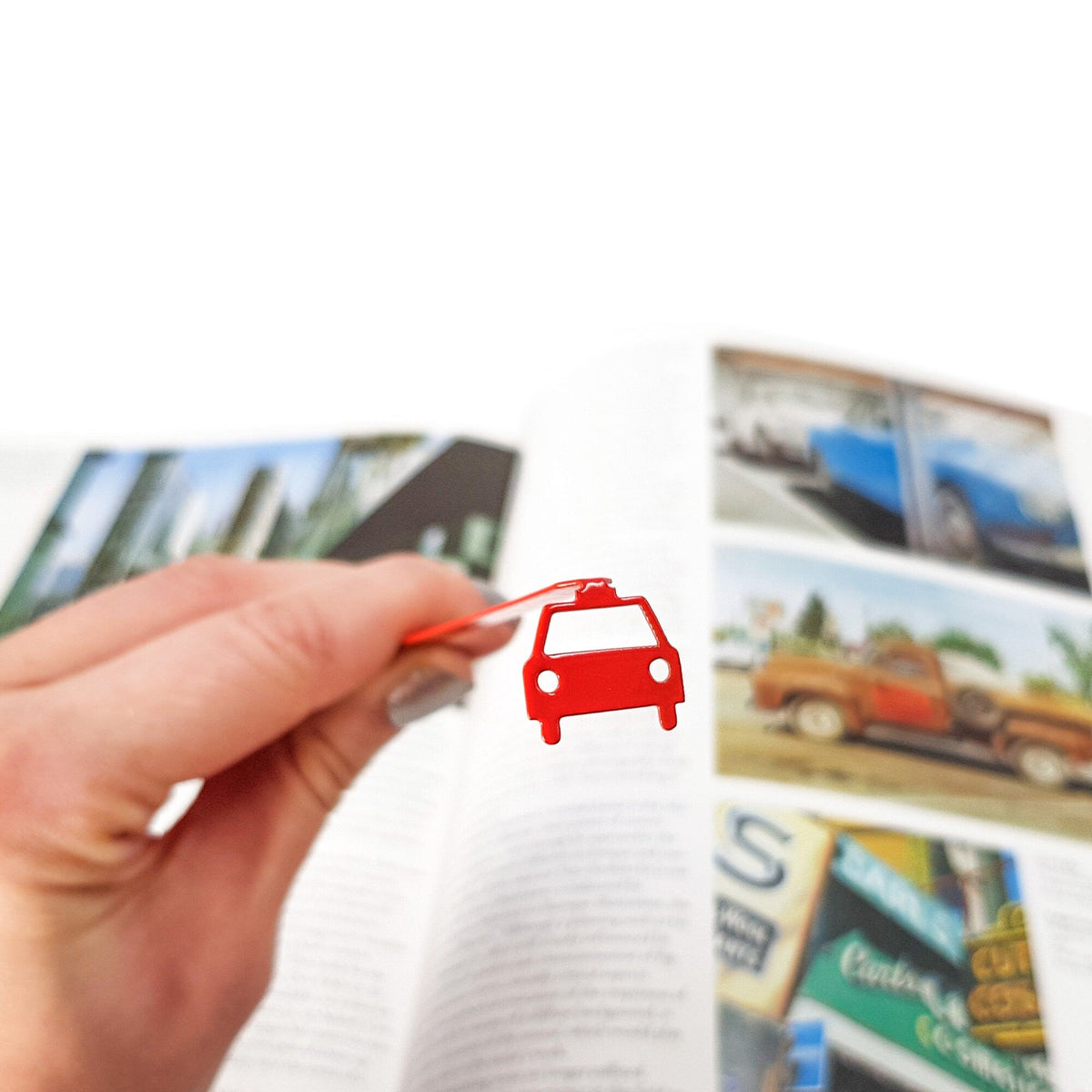 Car metal bookmark in red held in a hand above an open book