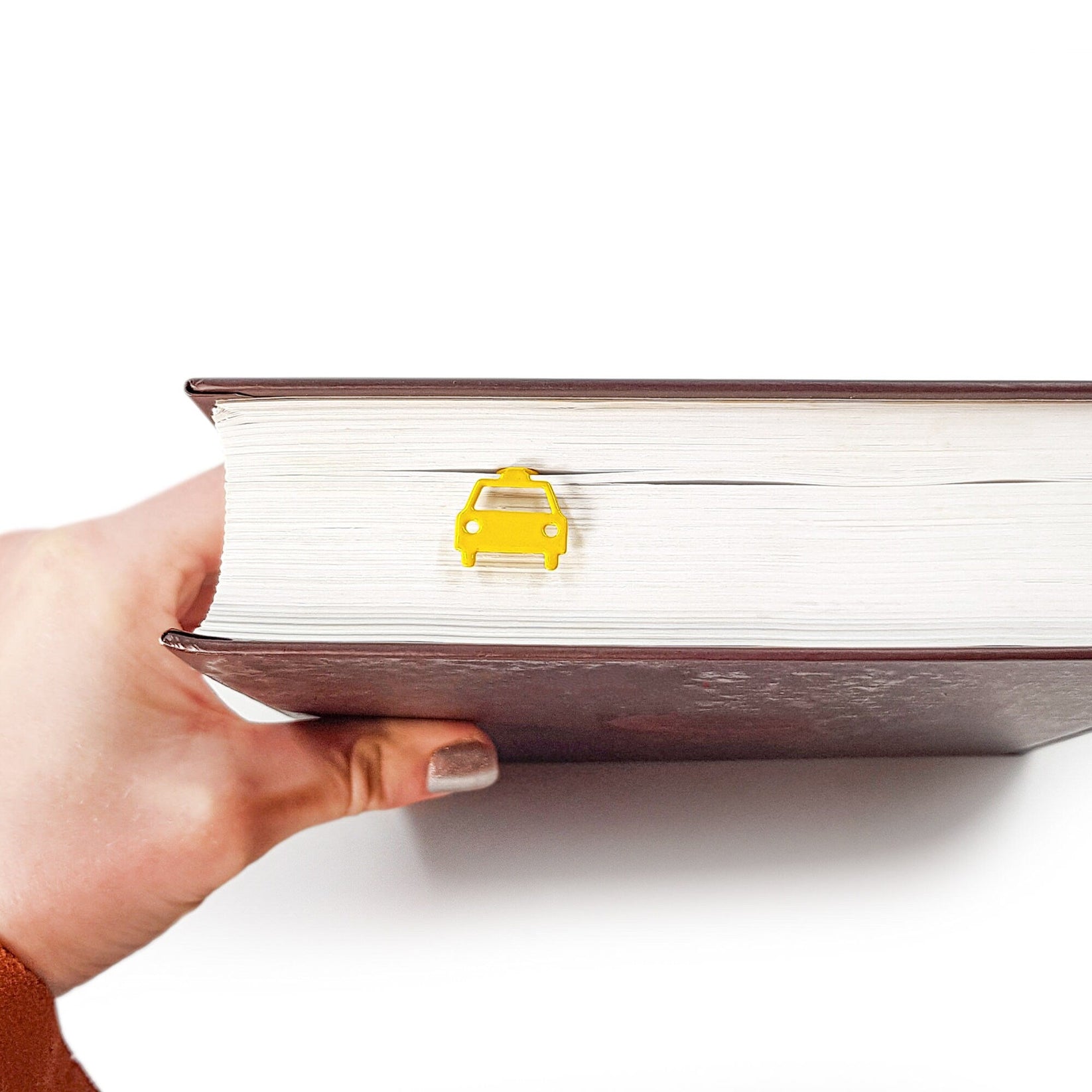 Car metal bookmark in gold held in a hand to show its size