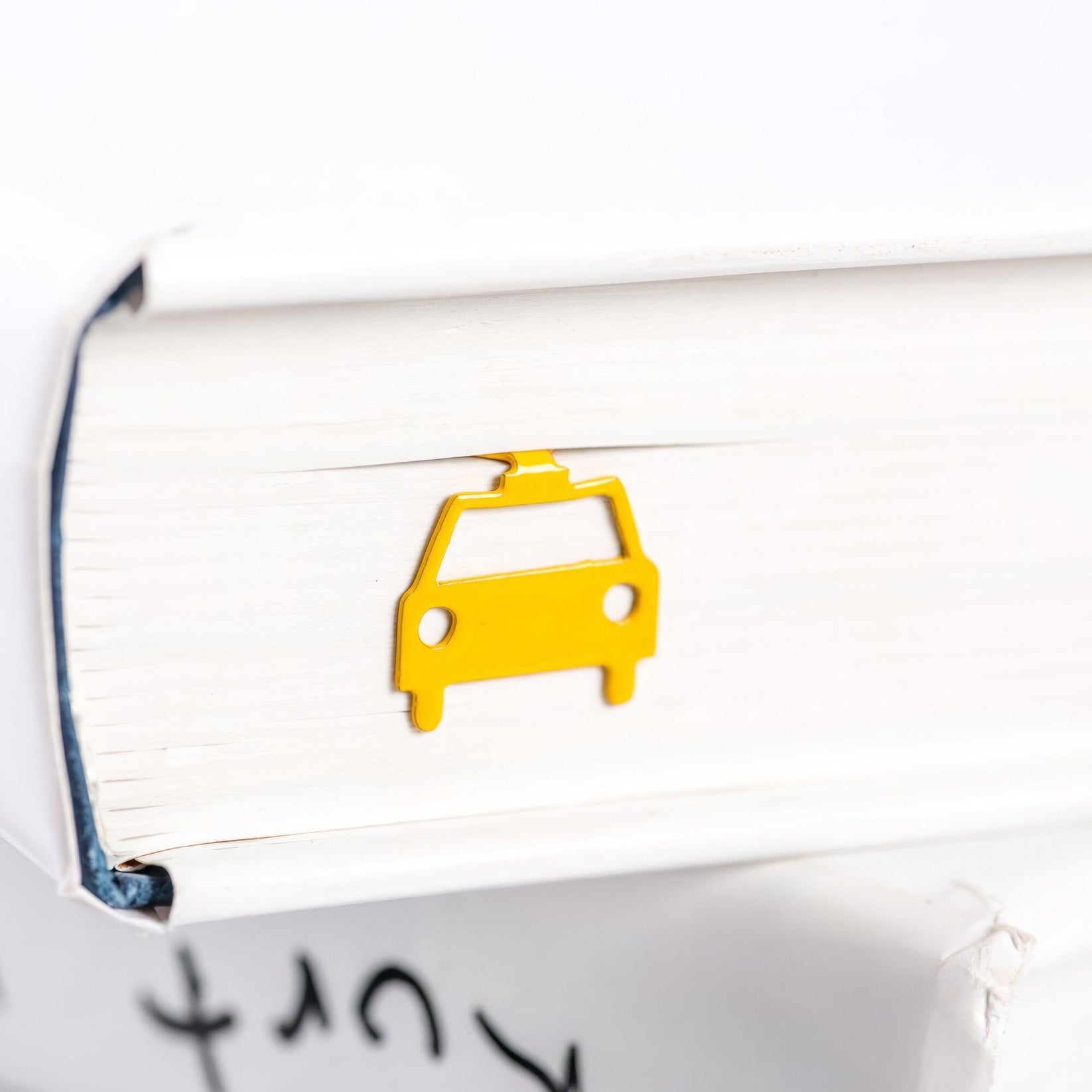 Car metal bookmark in gold in a closed book, only its top showing above the pages