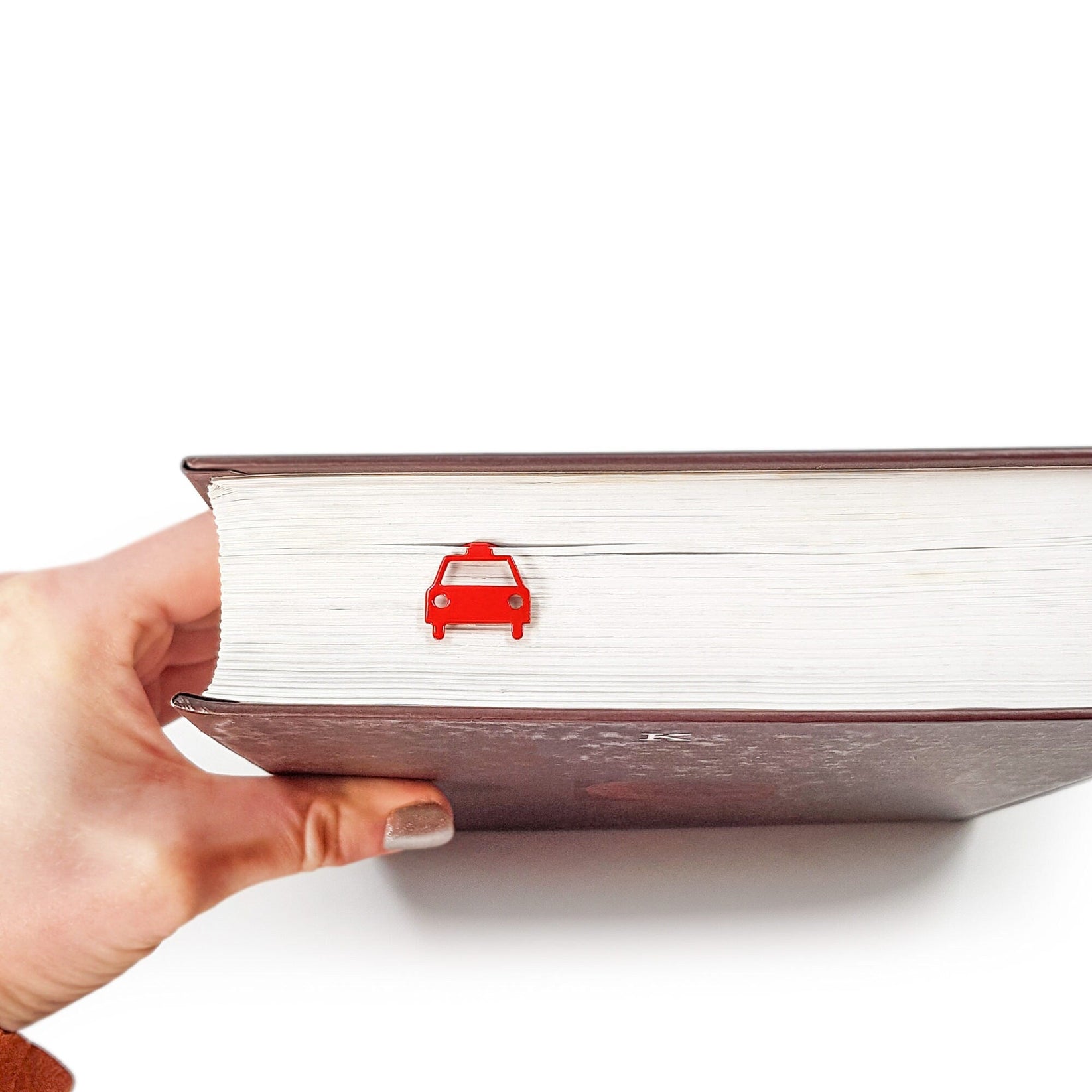 Car metal bookmark in red held over a book, seen from the front
