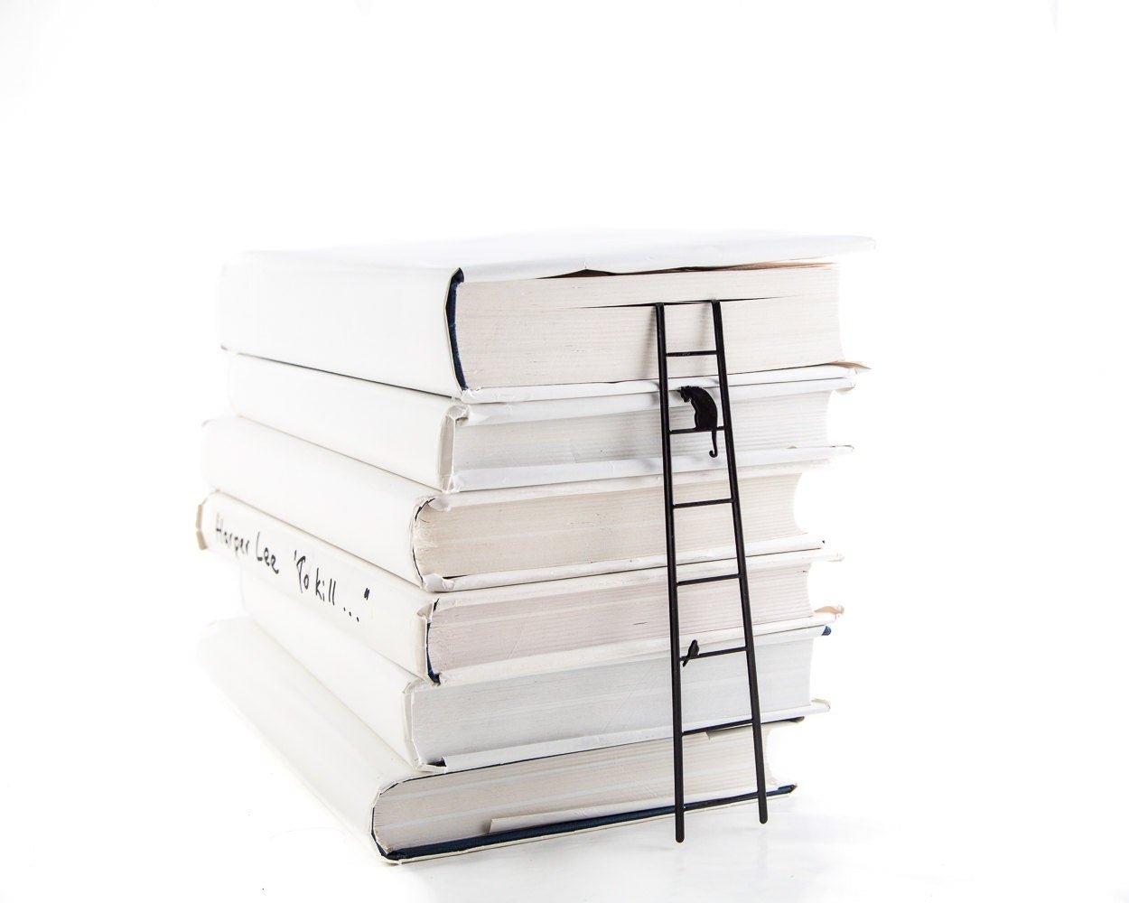 Cat and Bird on the Ladder metal bookmark shown with a stack of books