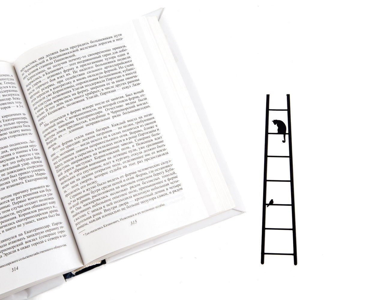 Cat and Bird on the Ladder metal bookmark marking a page in an open book