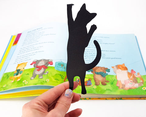 Cat Got Stuck metal bookmark marking a page in an illustrated book