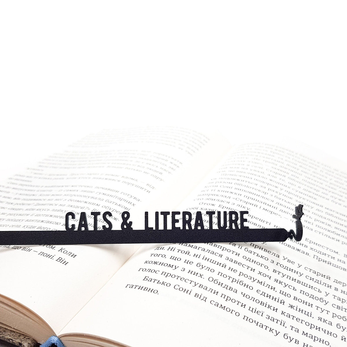Cats and Literature metal bookmark resting on the pages of an open book