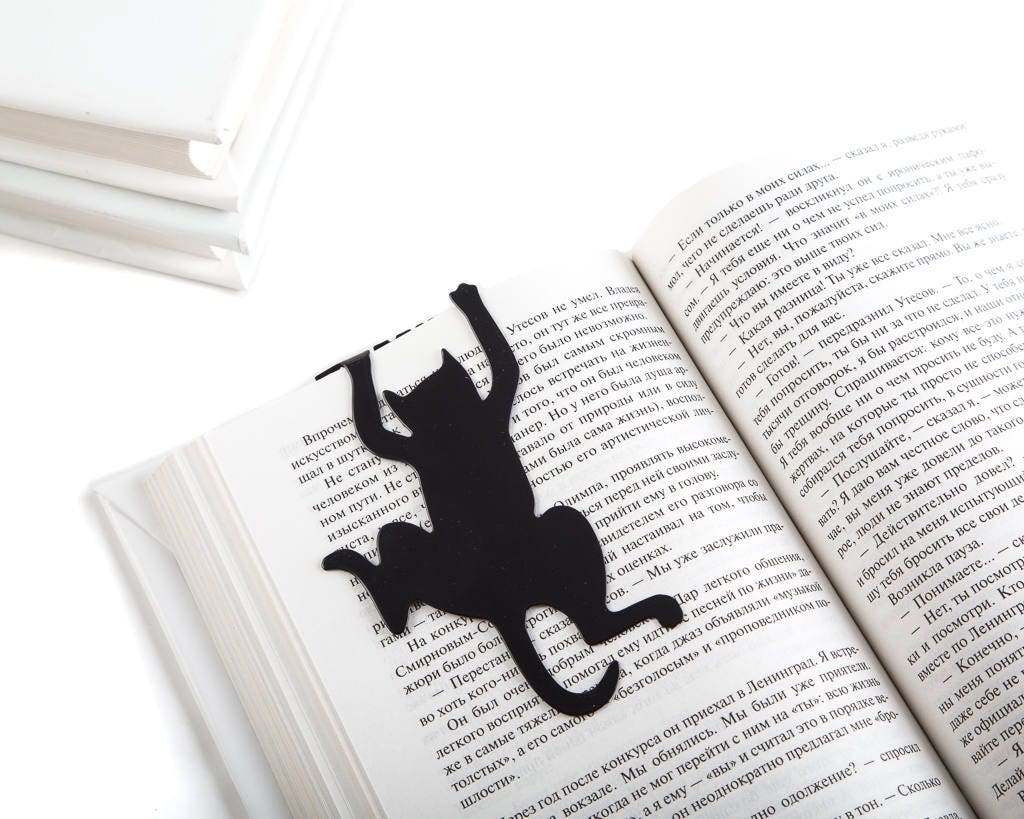 Cat's Library metal bookmark resting on the pages of an open book