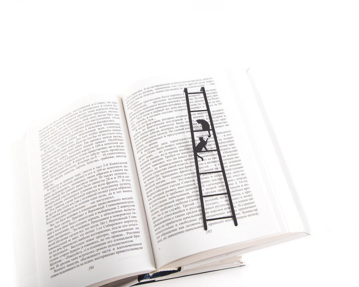 Cats on the Ladder metal bookmark resting on the pages of an open book