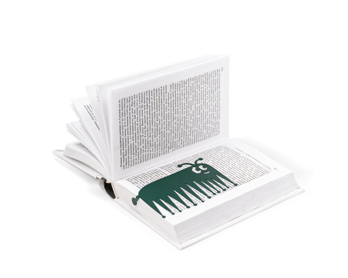 Charming Centipede metal bookmark in green marking a page in an open book