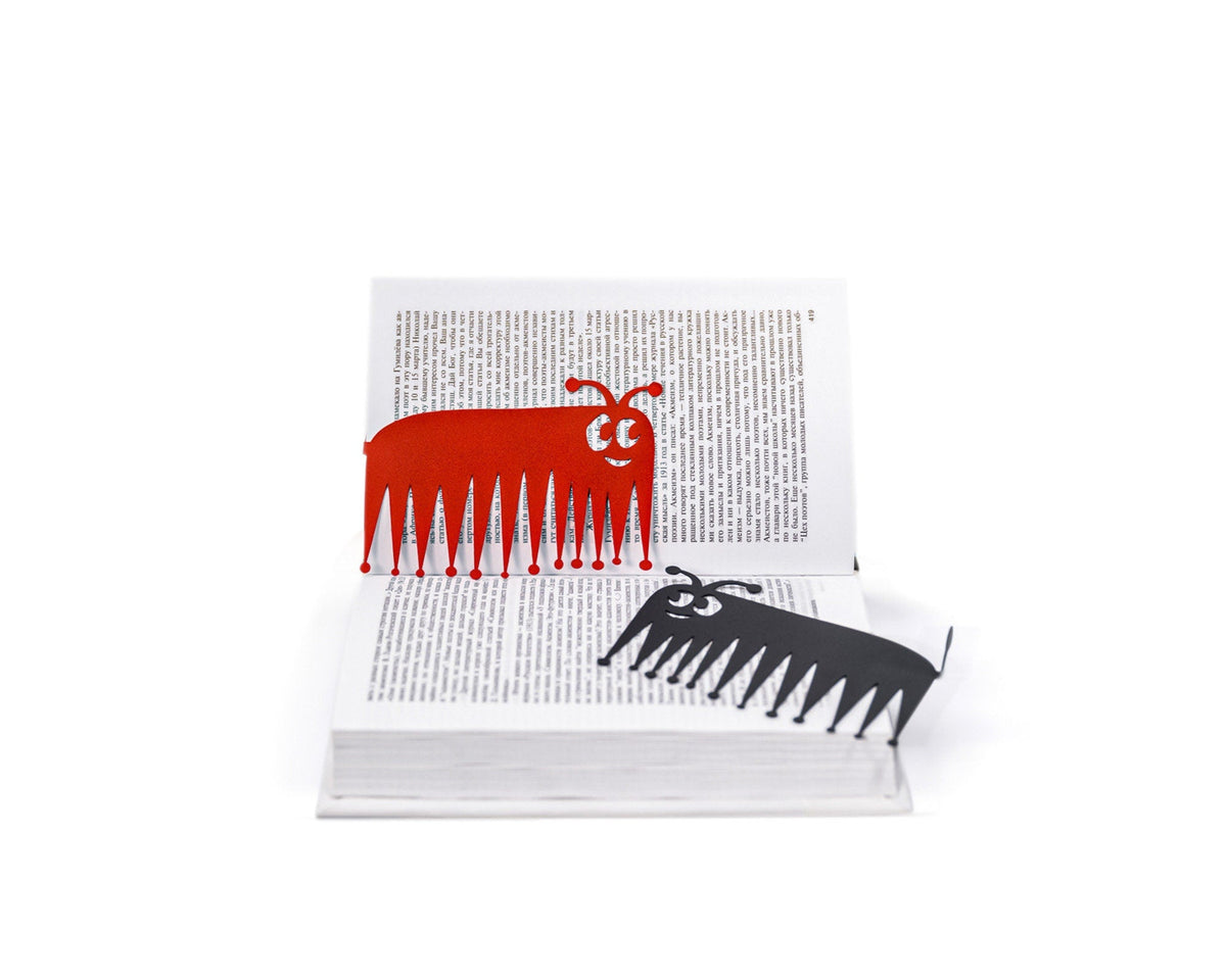 Charming Centipede metal bookmark in red lying across the pages of an open book