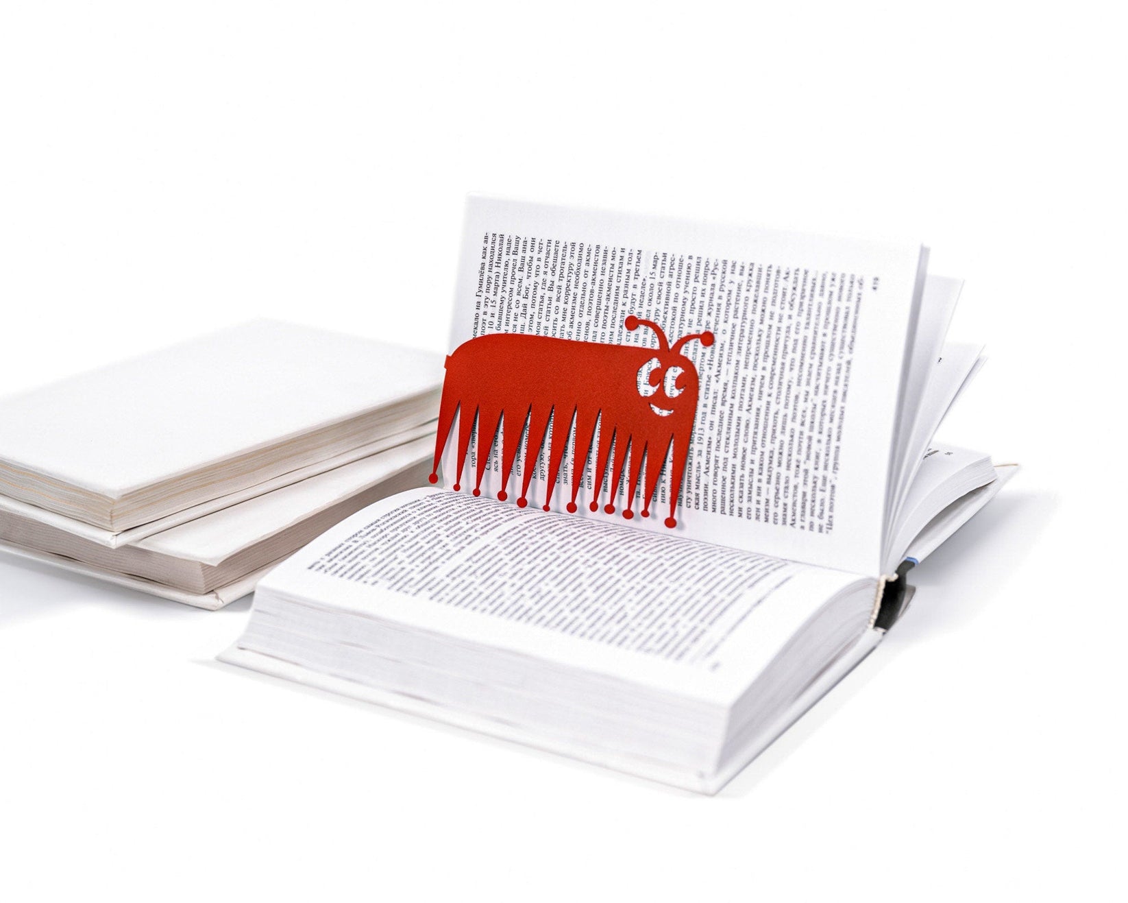 Charming Centipede metal bookmark in red lying on a stack of white books