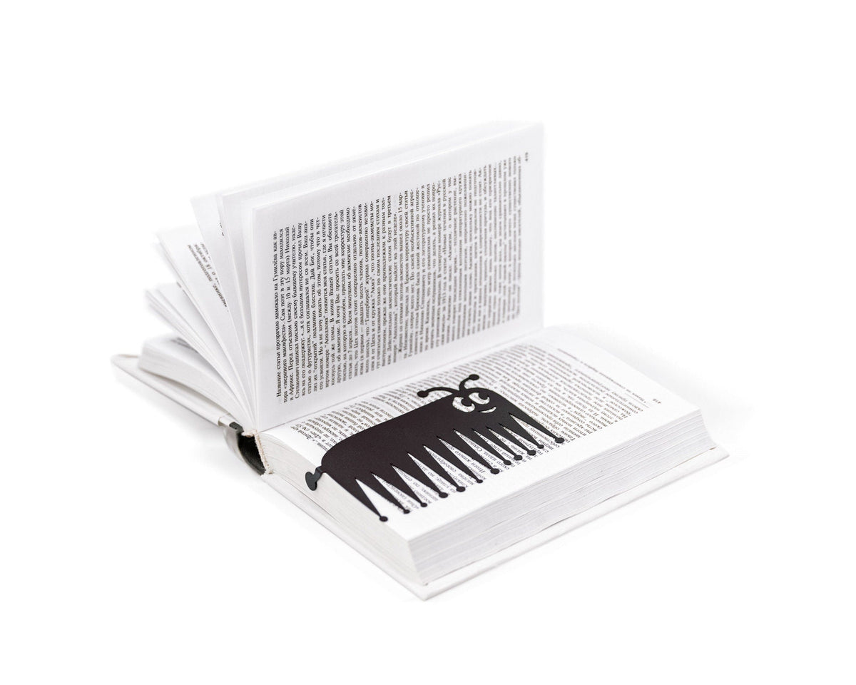 Charming Centipede metal bookmark resting on the pages of an open book