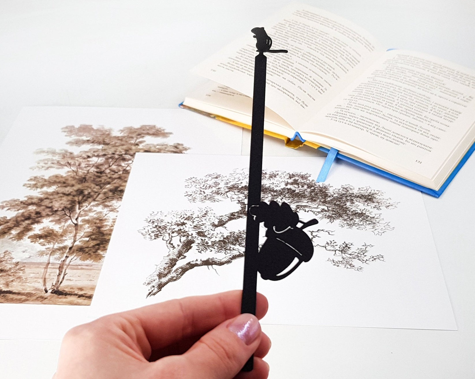 Chipmunk and the Acorn metal bookmark held in a hand above an open book