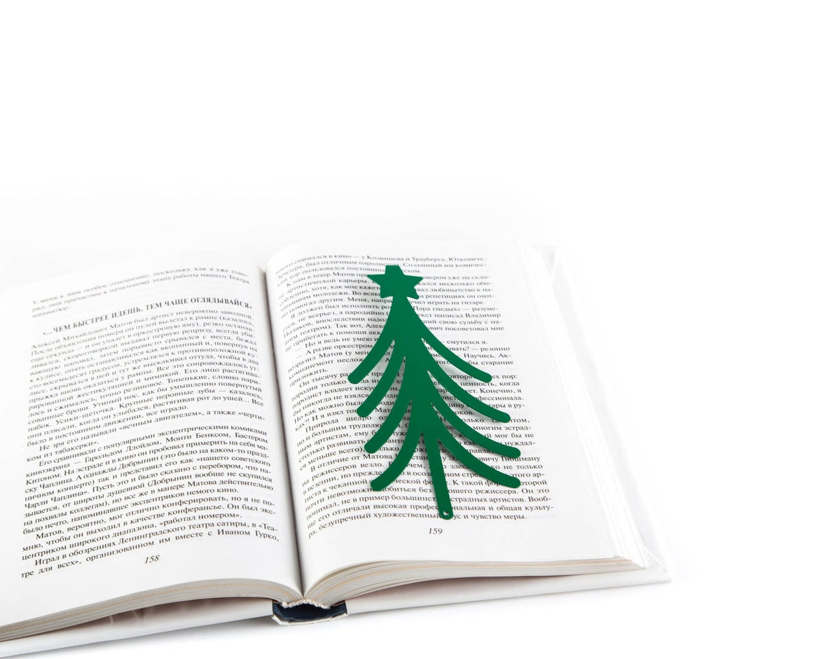 Christmas Tree metal bookmark in green marking a page in an open book